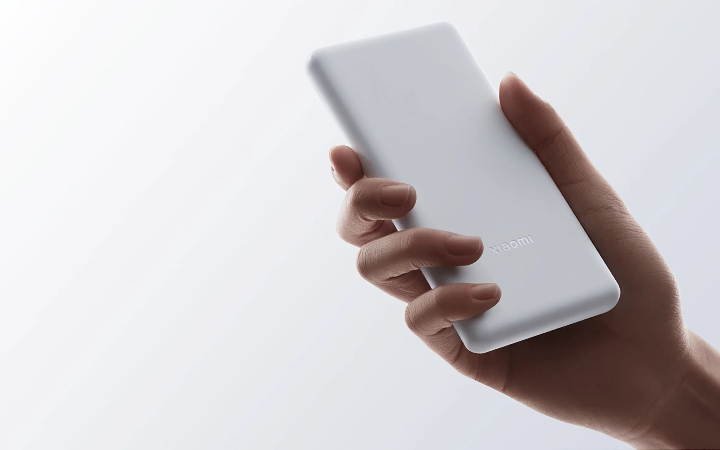 Dłoń trzymająca biały power bank. Widoczna nazwa marki 'xiaomi'.