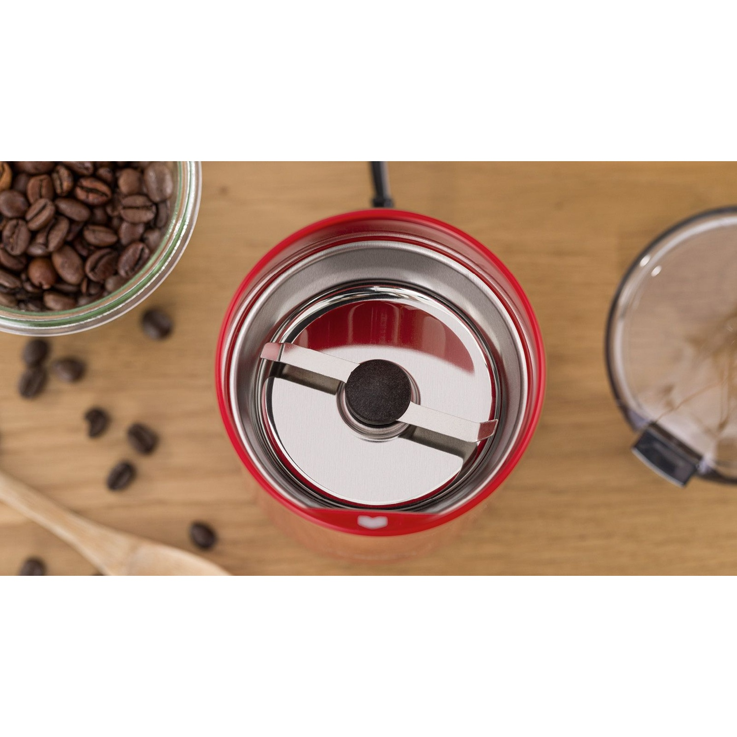 Una vista dall'alto di un macinacaffè rosso con chicchi di caffè sparsi.