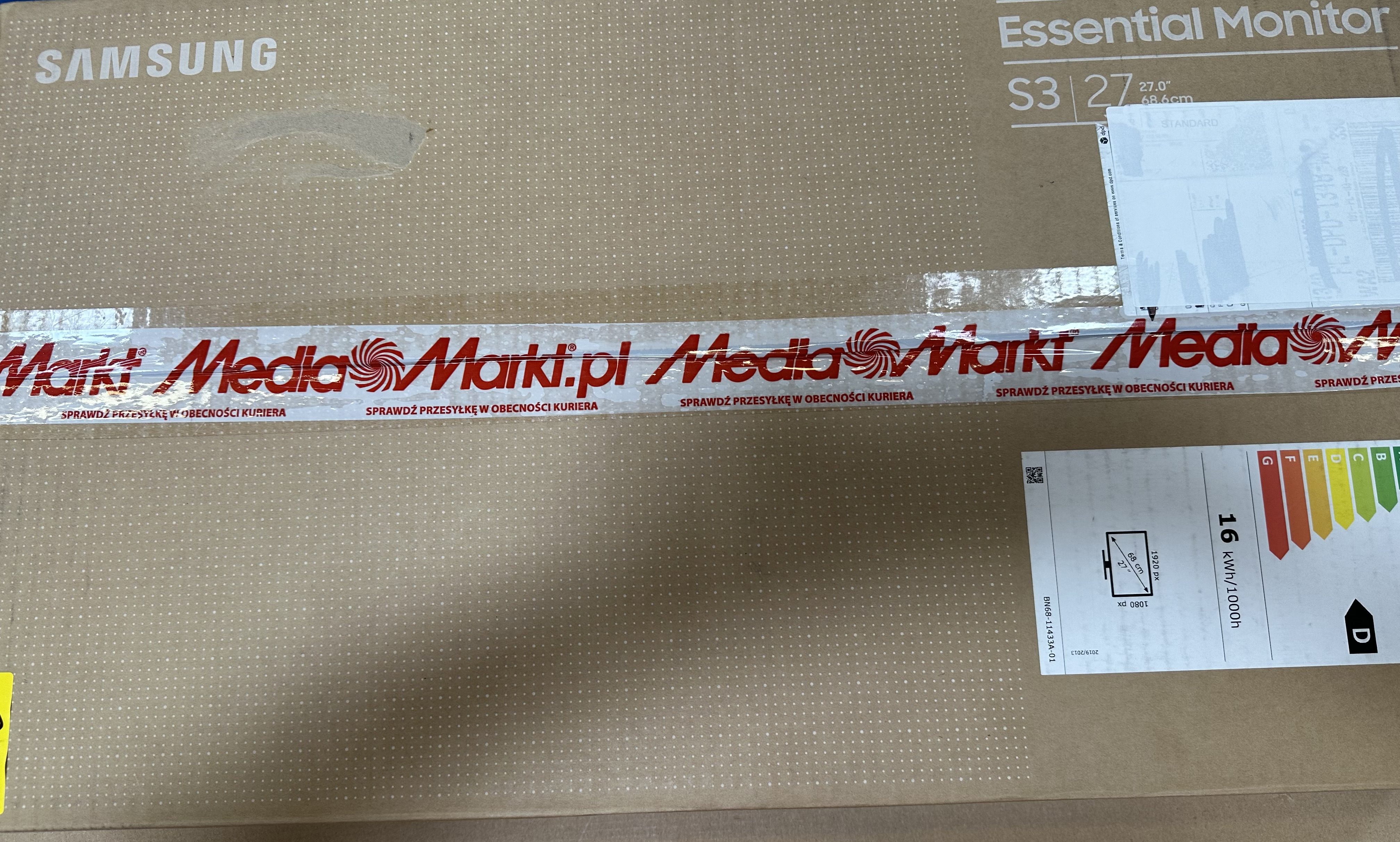 Kartowne pudełko z monitorem w środku, zaklejone taśmą z napisem 'Media Markt'.