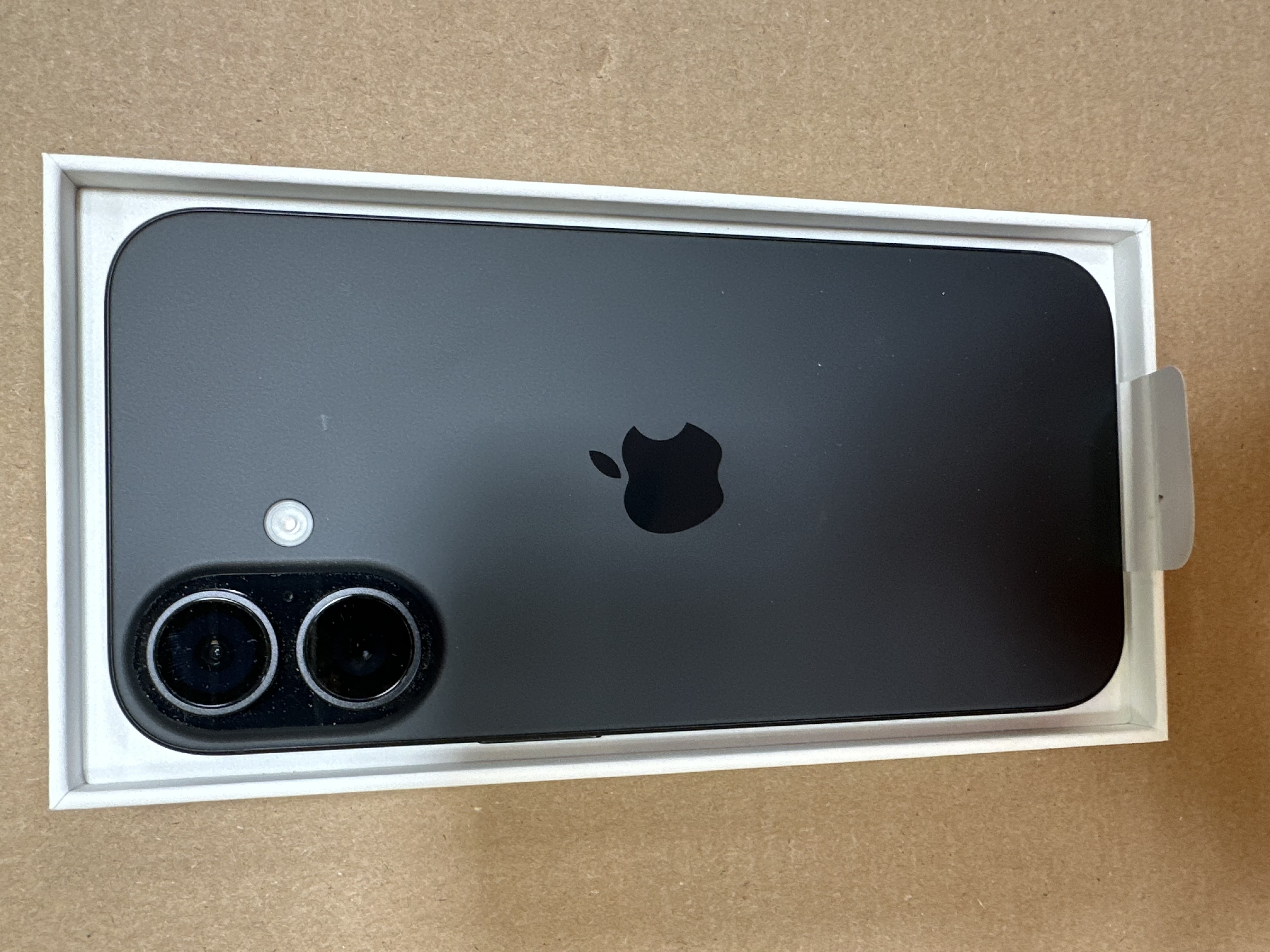 Tył czarnego iPhone'a w pudełku. Widoczne logo Apple i kamery.