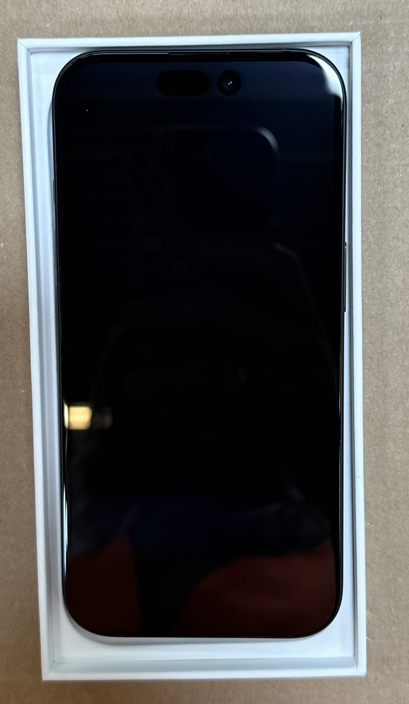 Czarny iPhone w białym pudełku. Ekran jest widoczny.