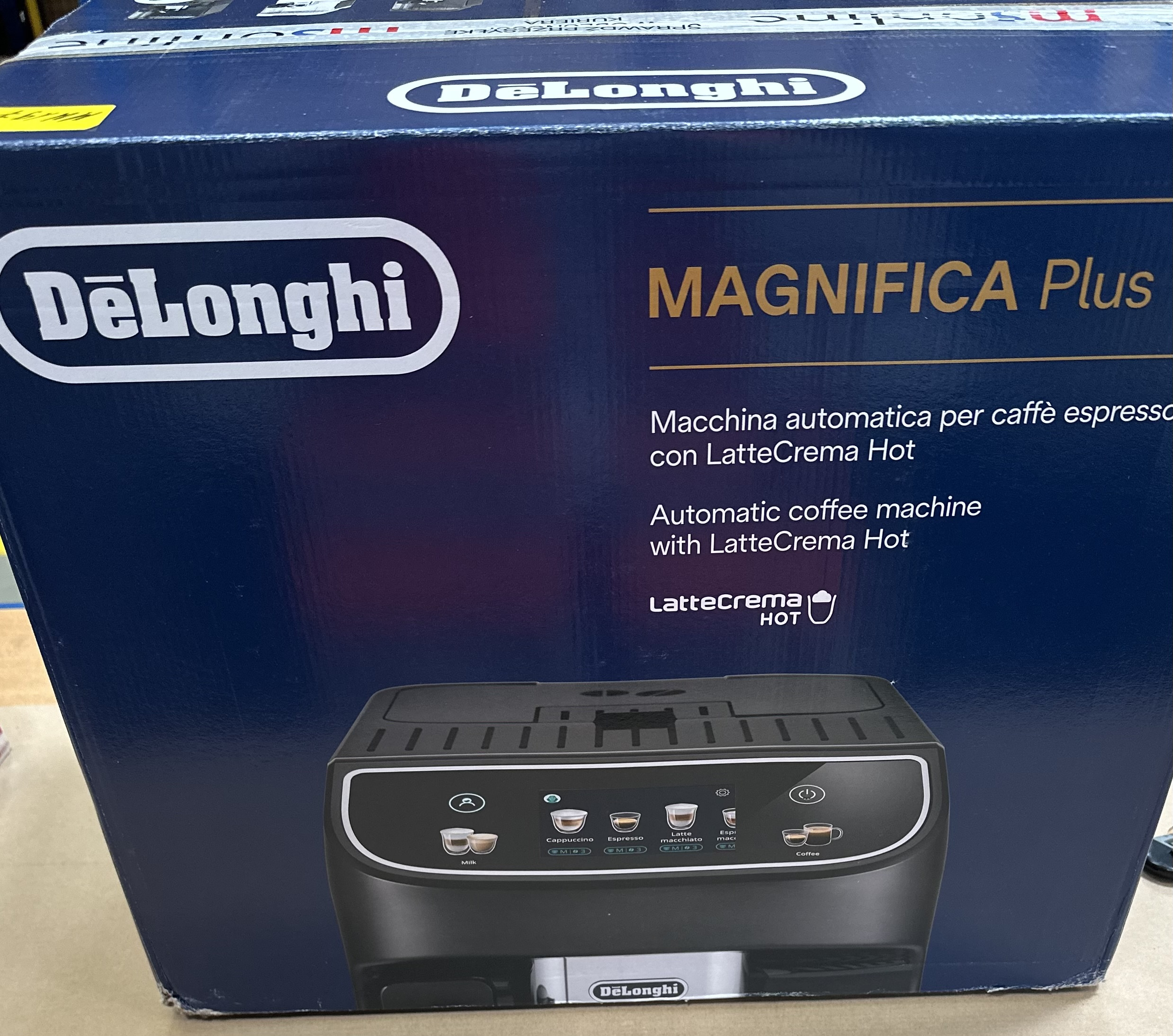 Pudełko ekspresu do kawy DeLonghi Magnifica Plus, z czarnym ekspresem do kawy z przodu.