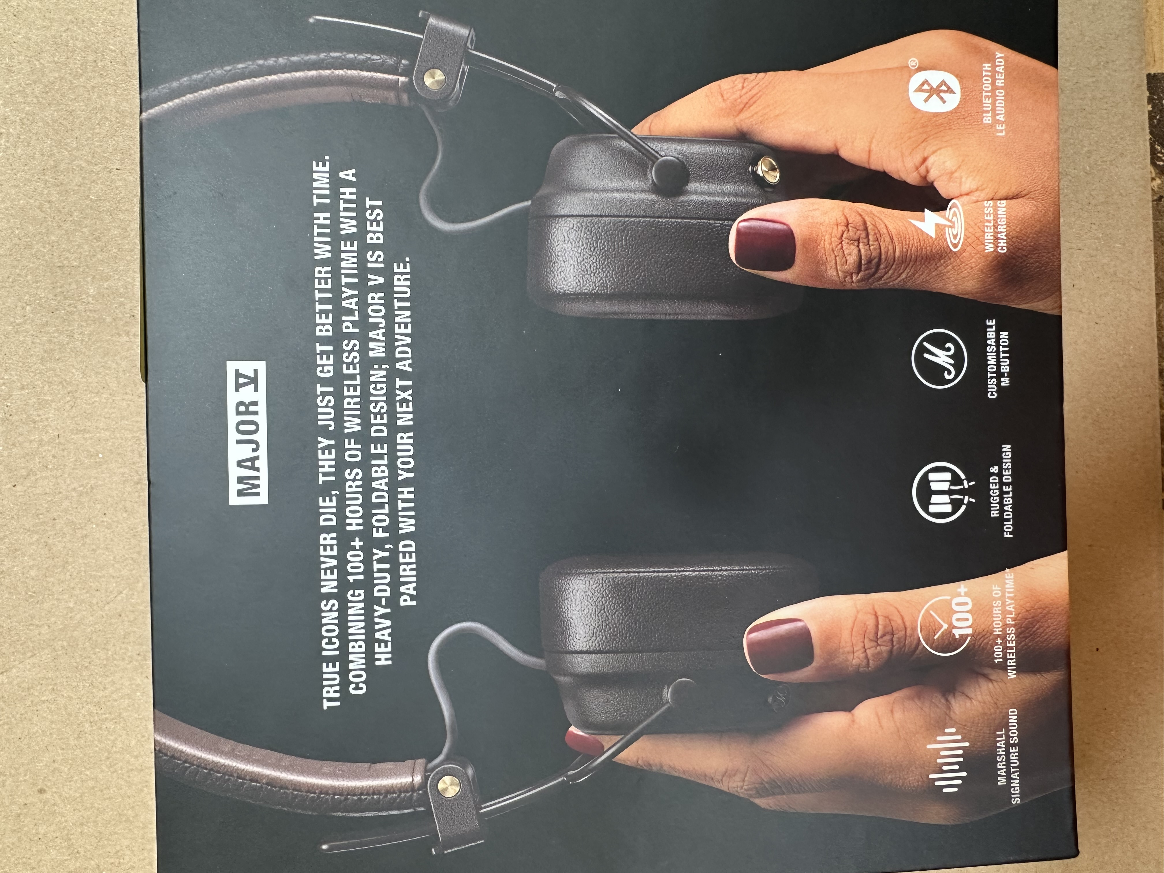 Słuchawki w pudełku. Dwie ręce trzymają słuchawki. Tekst o produkcie.