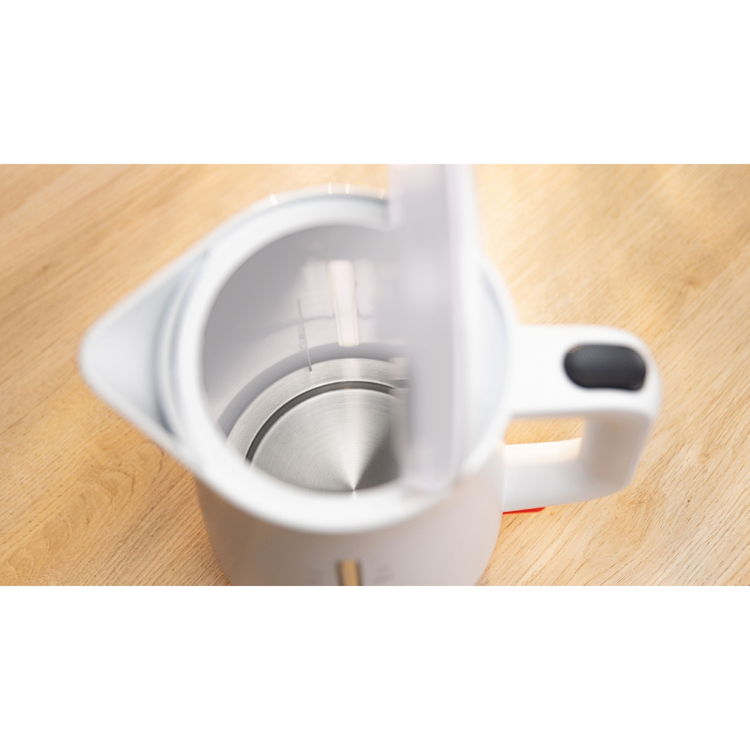 Vista interna di un bollitore elettrico bianco aperto con fondo in acciaio inox.