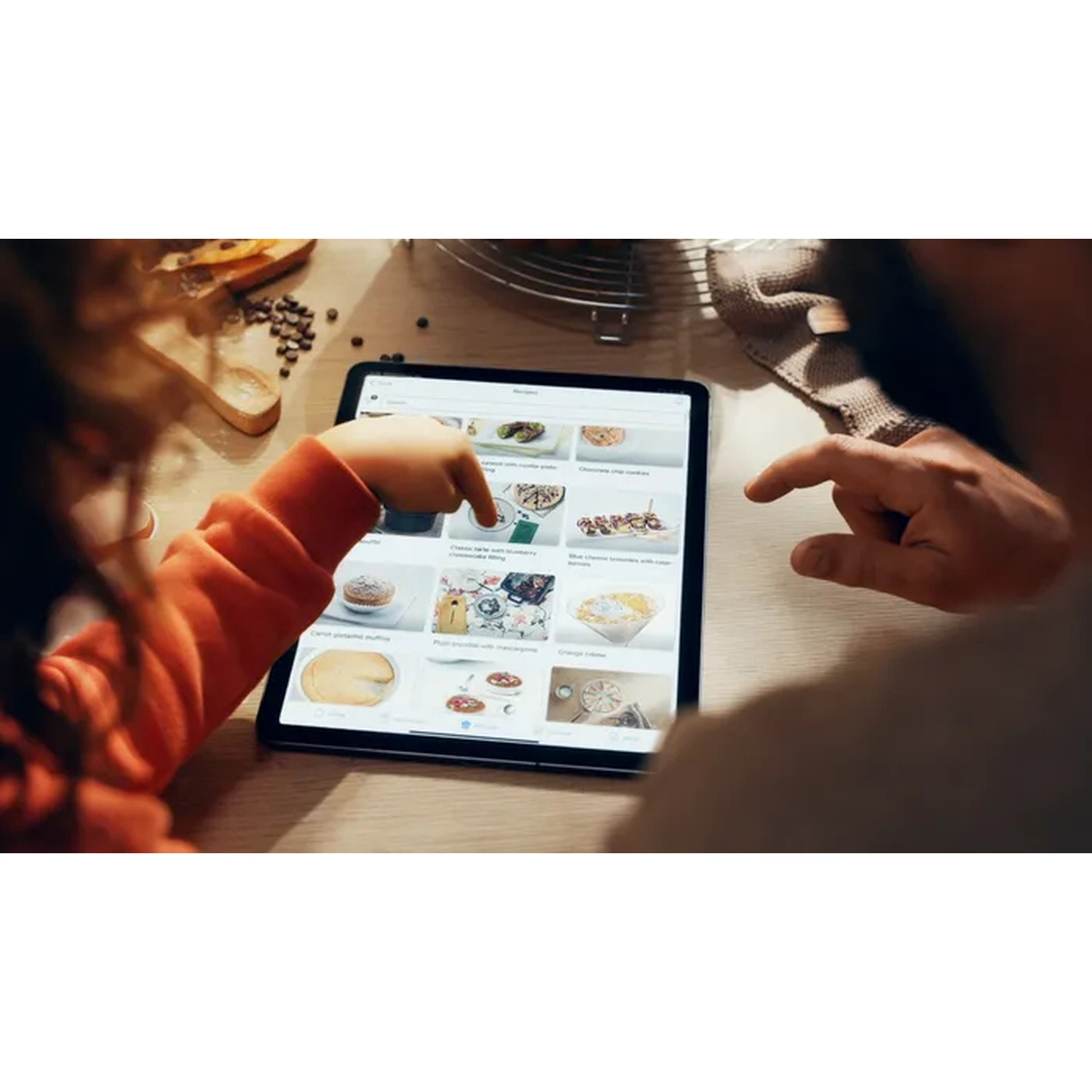 Bambino e adulto usano un tablet per visualizzare le ricette. Il tablet mostra una varietà di immagini di cibo.