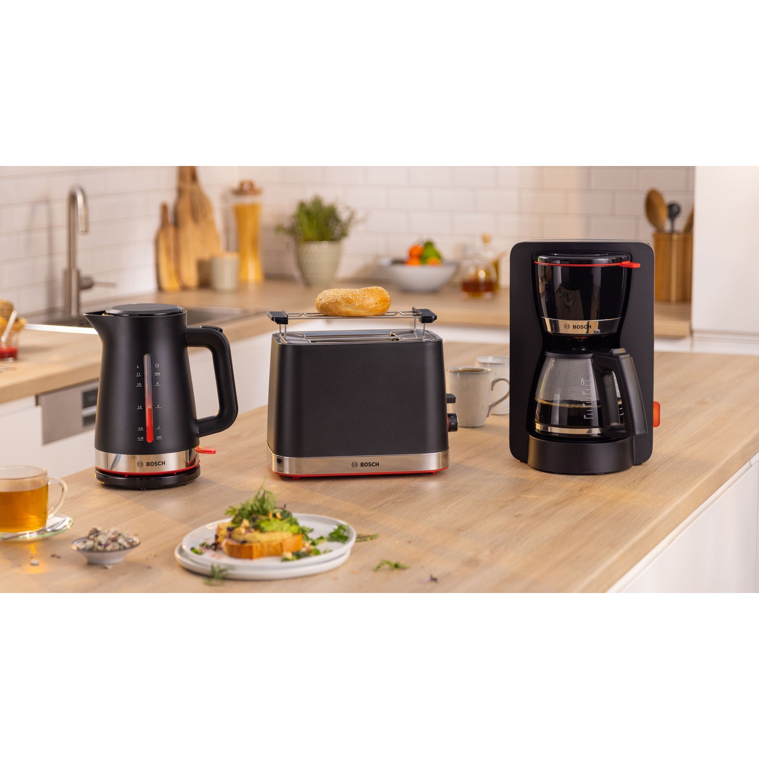 Elettrodomestici da cucina: bollitore, tostapane con bagel e macchina per il caffè su un bancone.