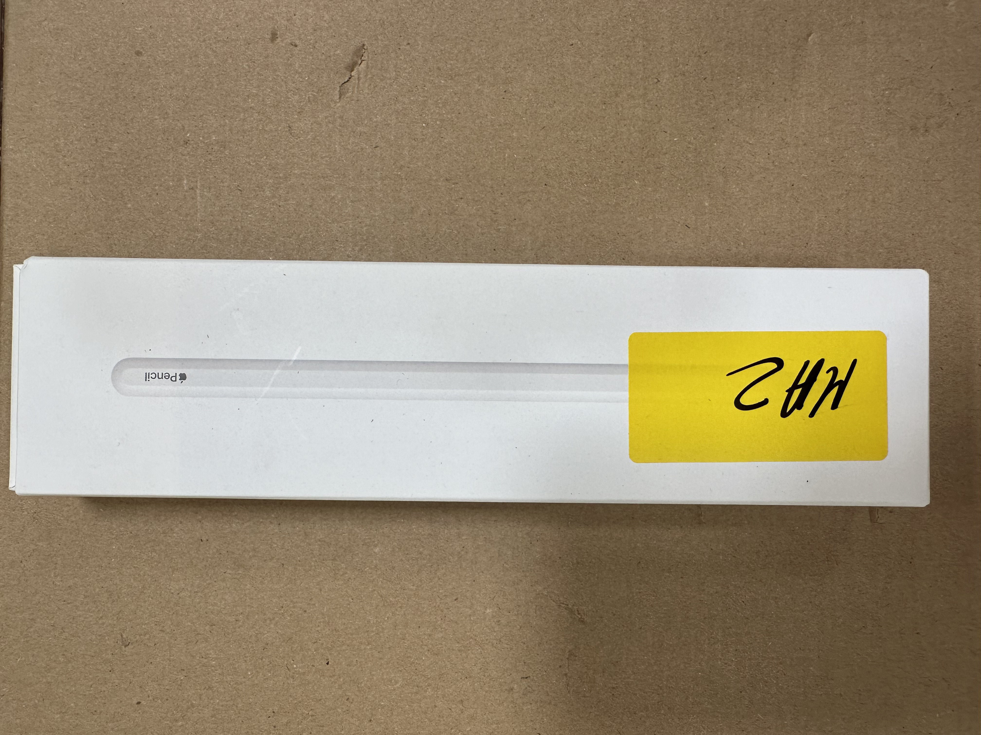 Białe prostokątne pudełko z Apple Pencil i żółtą naklejką.