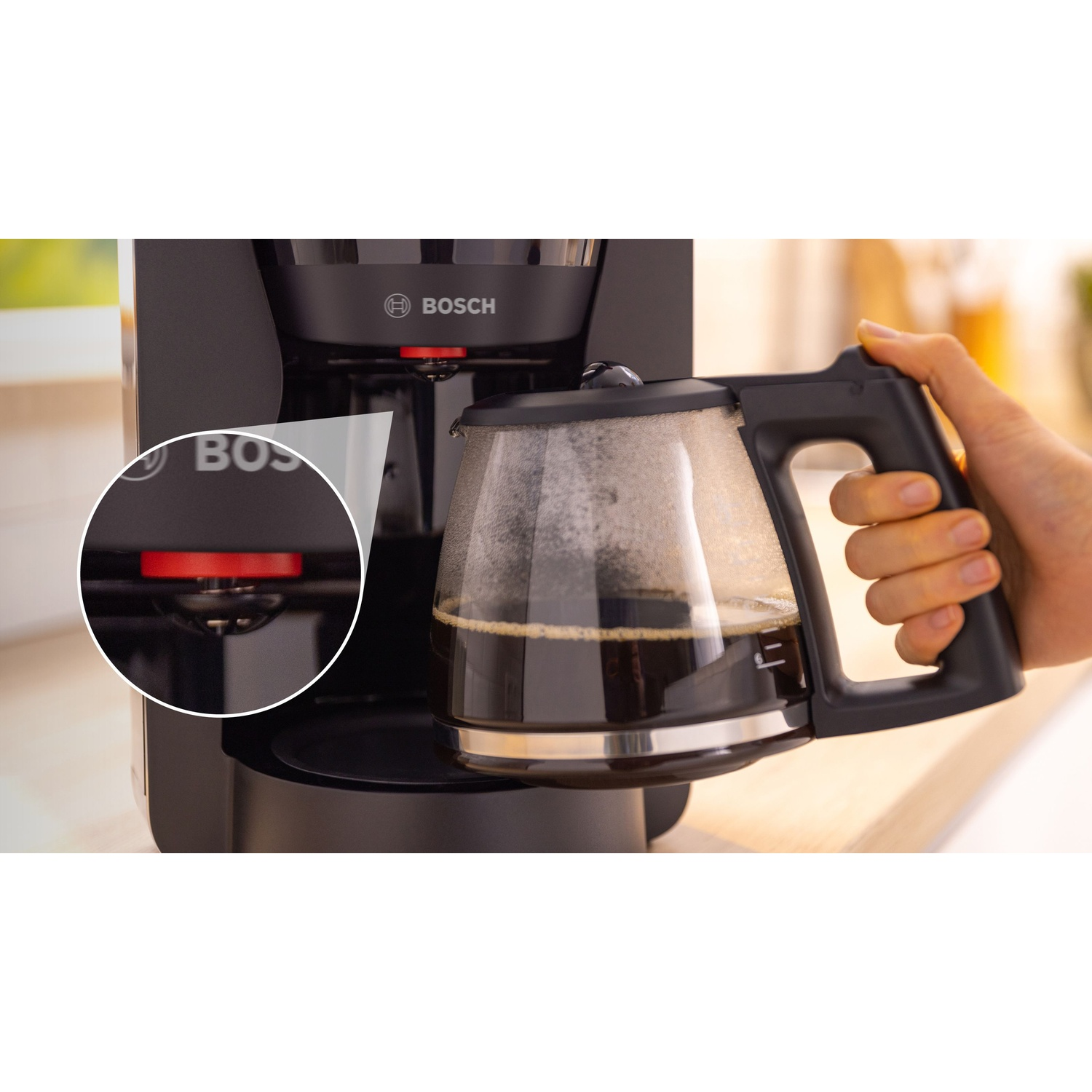 Macchina per il caffè con una mano che tiene una caraffa piena, primo piano.