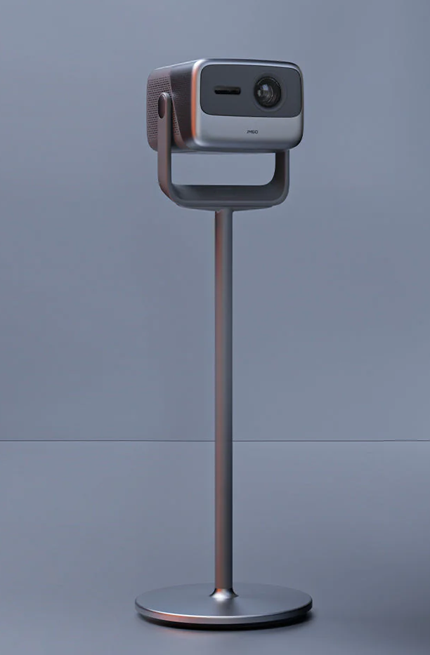 Un projecteur sur un support. Le projecteur est argenté et noir. Le support a une base ronde et un long poteau.