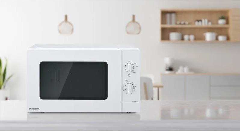 Micro-ondes blanc sur un comptoir avec deux boutons de commande.