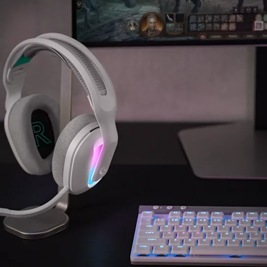 Fehér és szürke gamer headset állványon, billentyűzet és monitor.