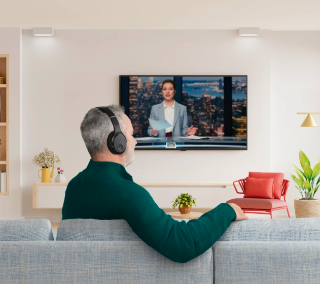 Hombre viendo la televisión con auriculares.