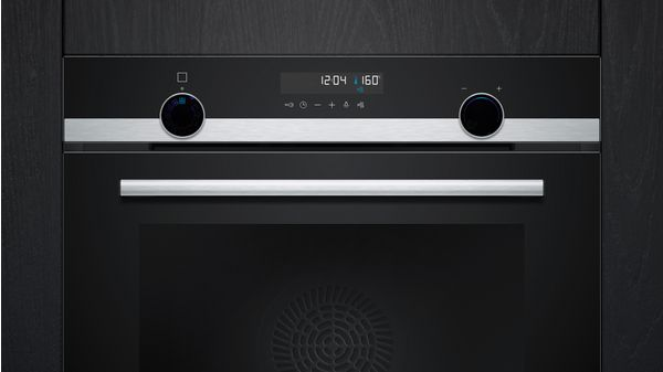 Horno negro con pantalla digital y perillas. Manija plateada debajo de la puerta.
