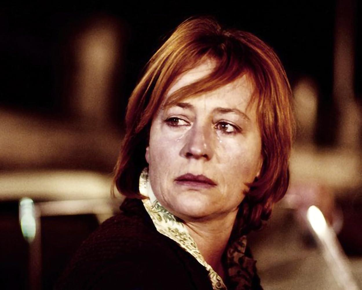 Eine Frau mit Tränen im Gesicht schaut zur Seite. Dunkler Hintergrund und ein Licht rechts.
