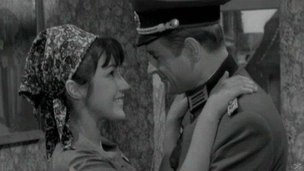 Schwarzweißfoto einer Frau und eines Mannes in Uniform. Sie lächeln und umarmen sich.