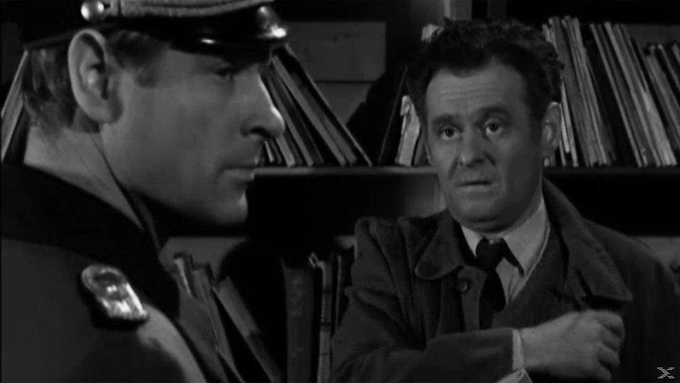 Schwarzweiß-Standbild aus einem Film. Zwei Männer in einem Raum, einer in Uniform, blickt den anderen mit besorgtem Gesichtsausdruck an.