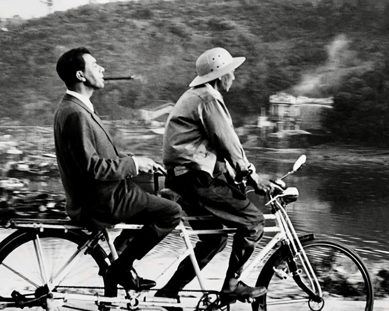 Schwarzweißbild von zwei Männern, die Tandemfahrrad fahren.