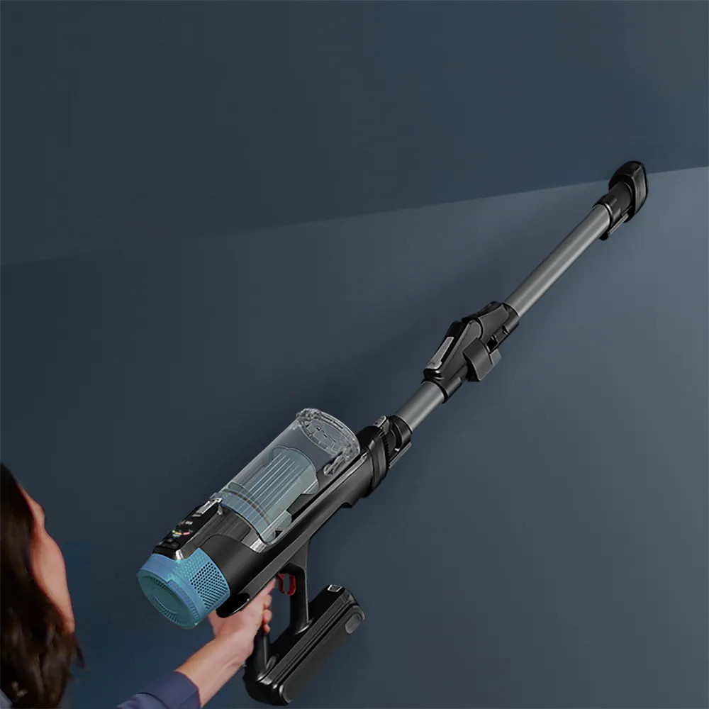 Kobieta używa czarno-szarego odkurzacza bezprzewodowego na niebieskiej ścianie.