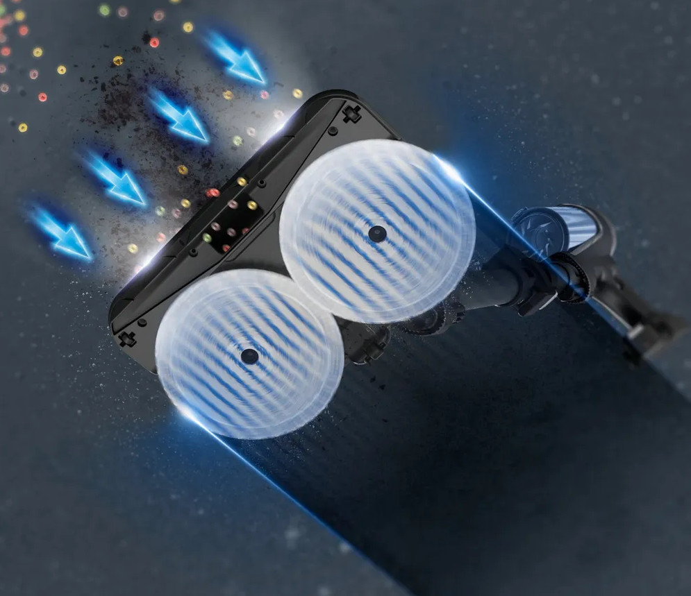 Zbliżenie głowicy odkurzacza z dwiema obracającymi się szczotkami i strzałkami wskazującymi przepływ powietrza.