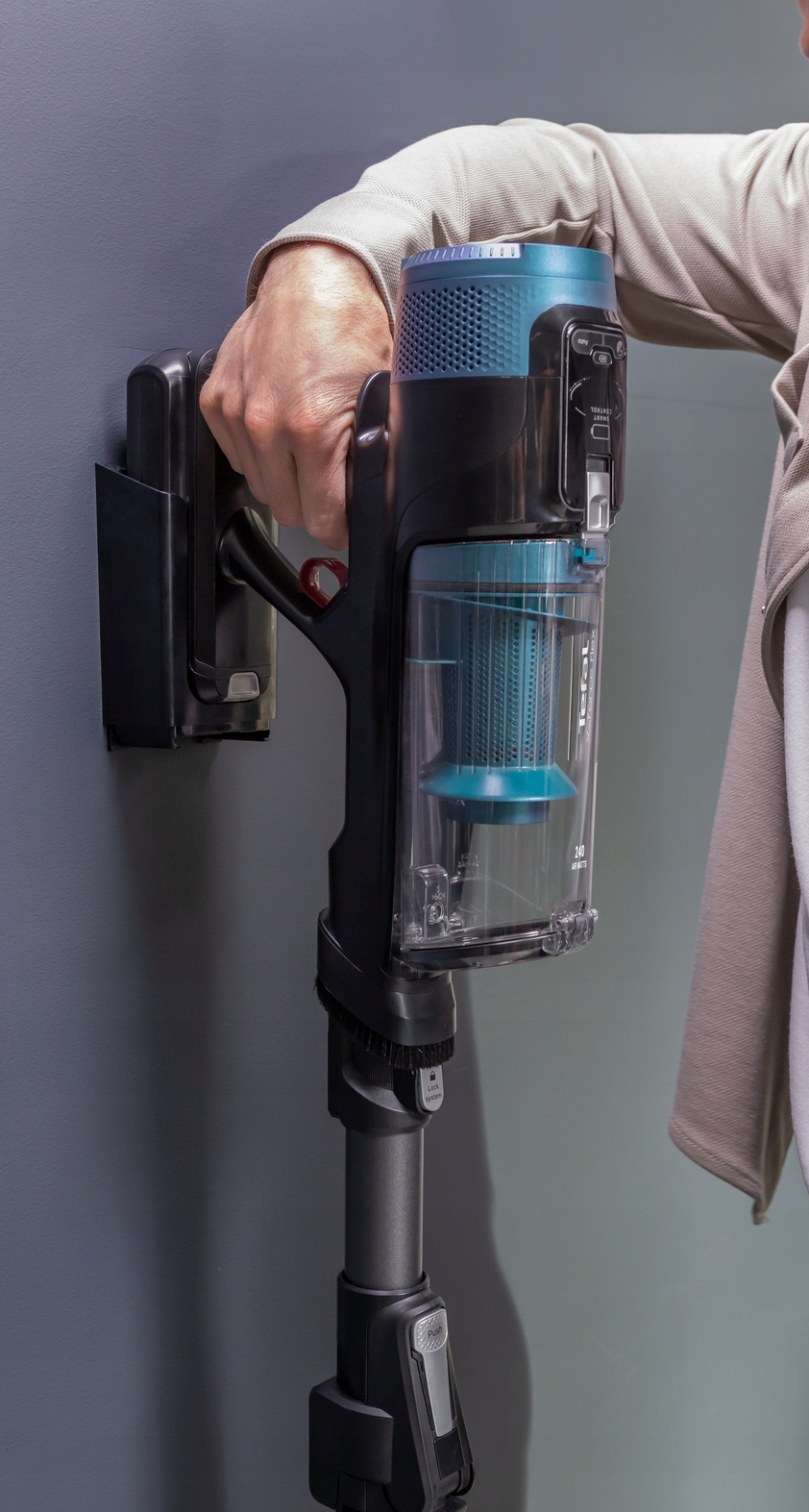 Ręka osoby trzymająca odkurzacz przy ścianie.