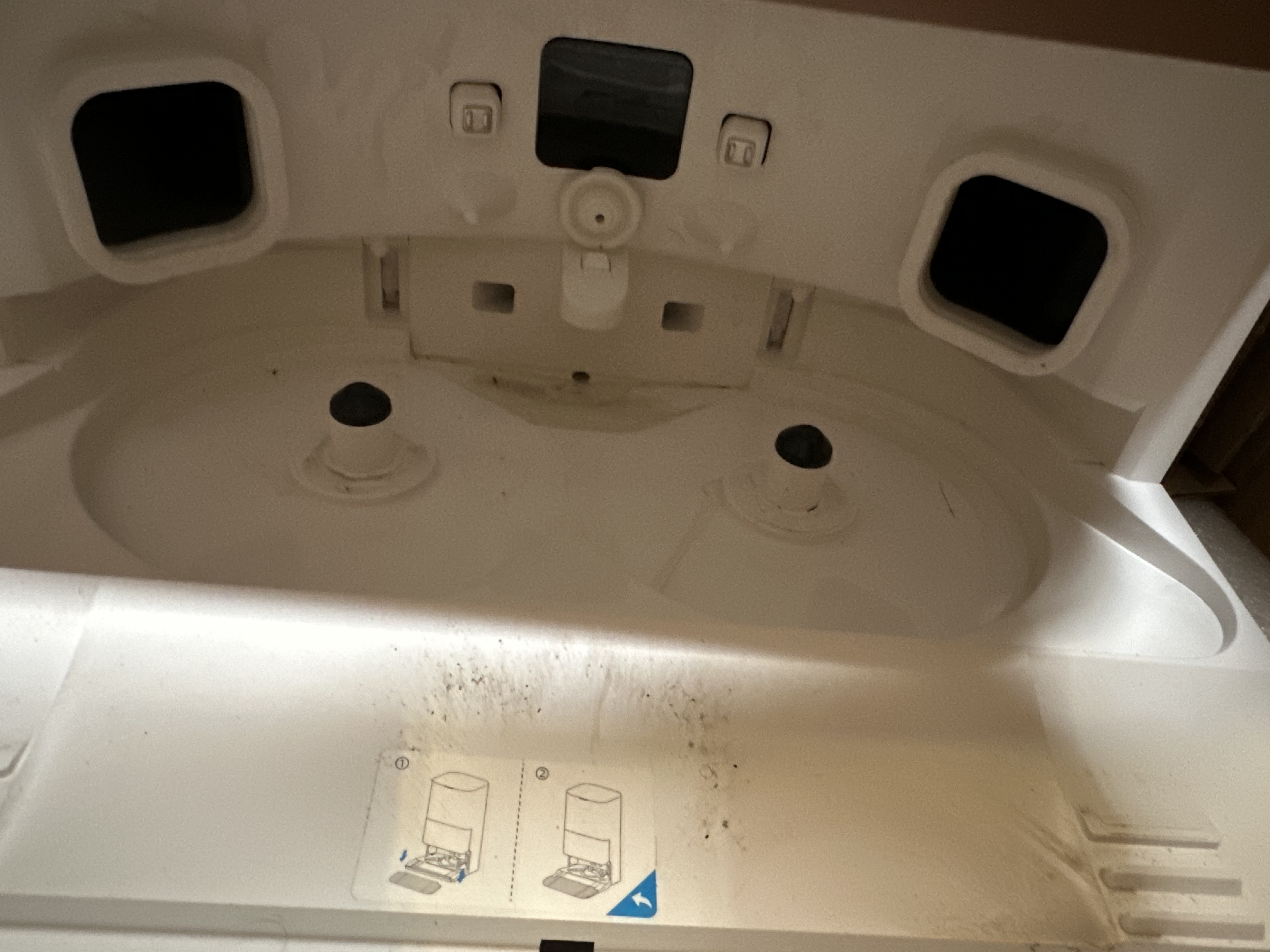 Wnętrze białego urządzenia, z różnymi przegrodami i otworami, wygląda na lodówkę.