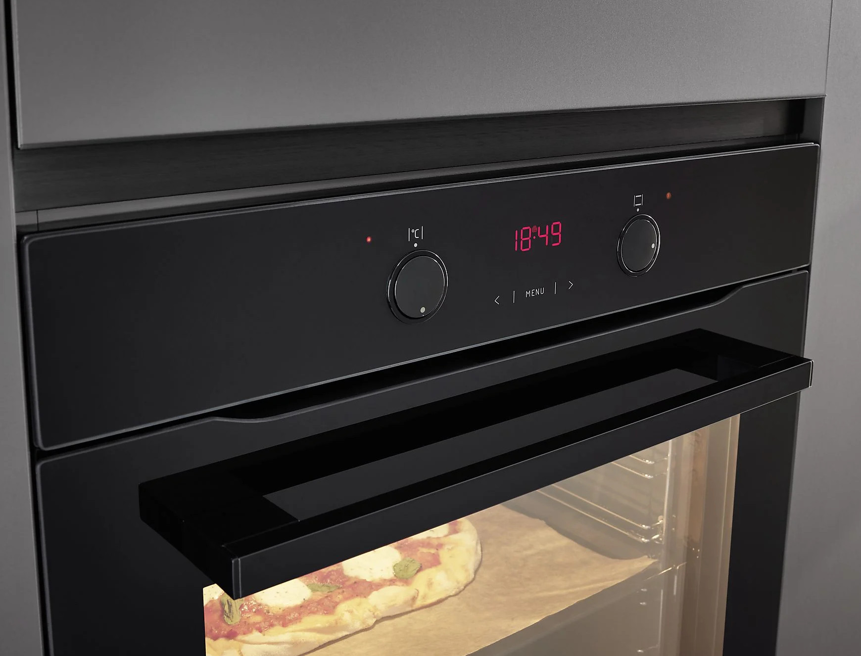 Czarny piekarnik z cyfrowym wyświetlaczem pokazującym godzinę i ustawienia, z pizzą w środku.