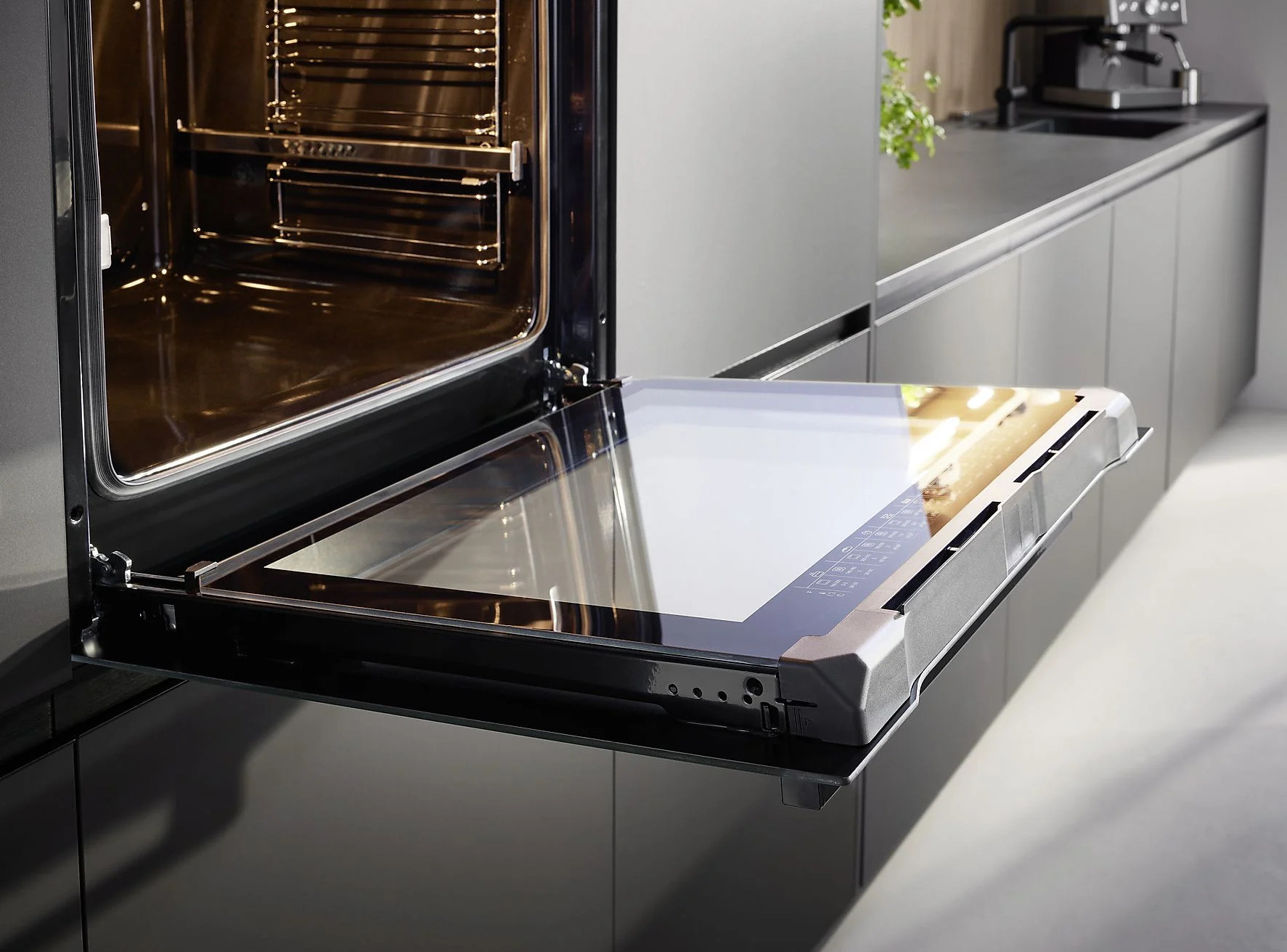 Zbliżenie otwartych drzwi piekarnika, wnętrze ze stali nierdzewnej i szklany panel.