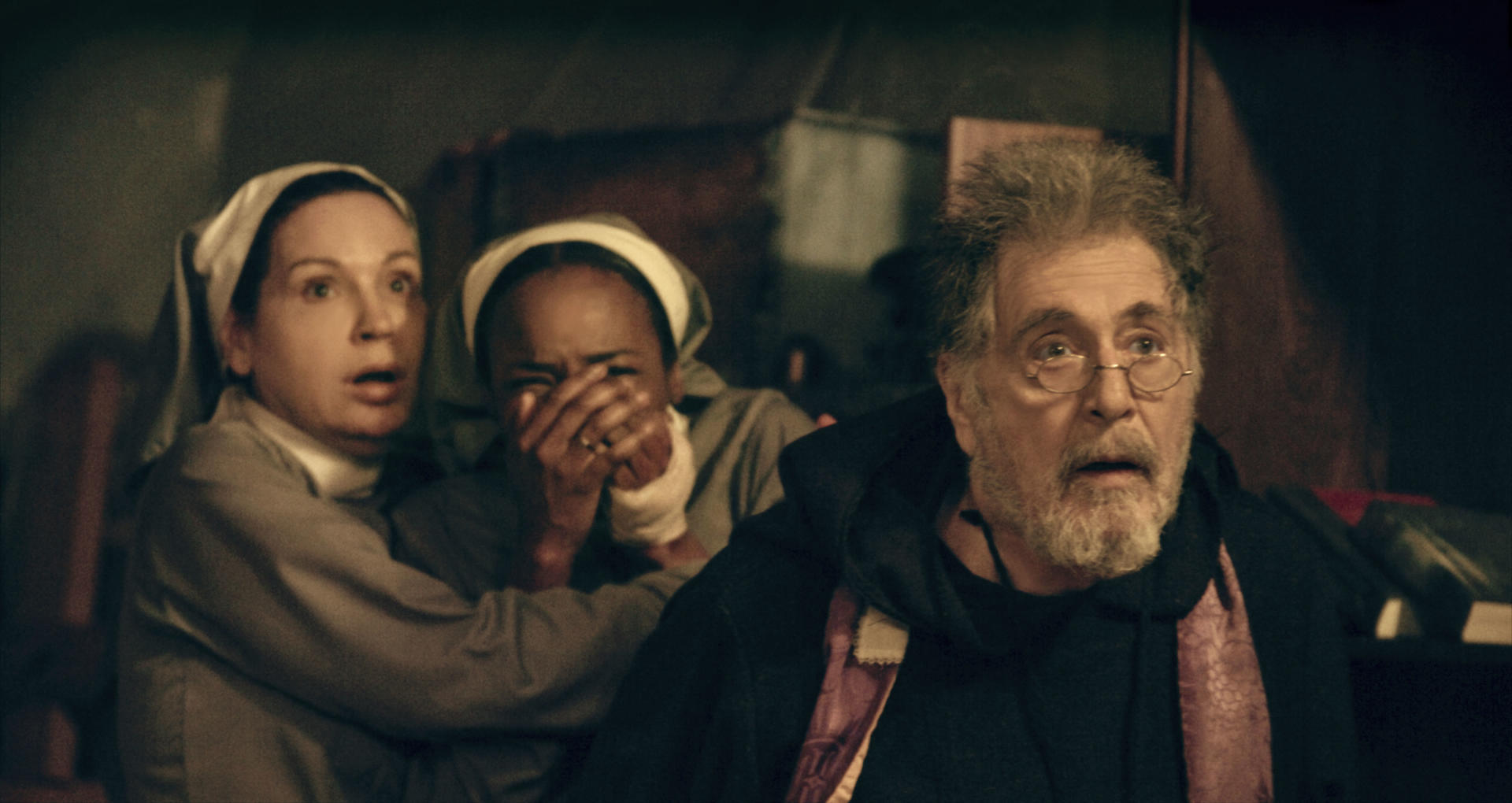 Eine Filmszene mit drei Personen mit schockierten Gesichtsausdrücken.
