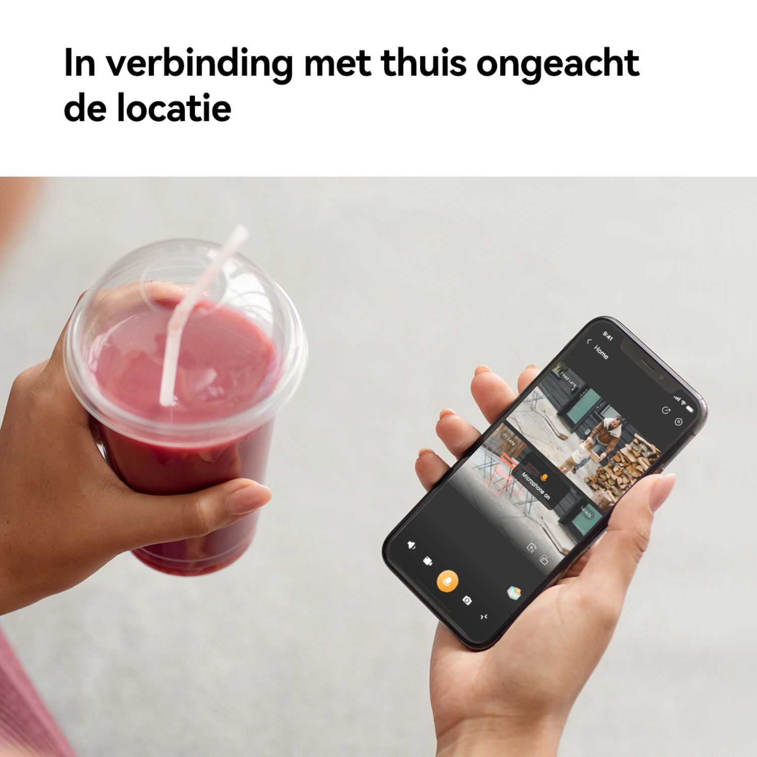 Person holding a drink, looking at a phone showing a home security camera view.