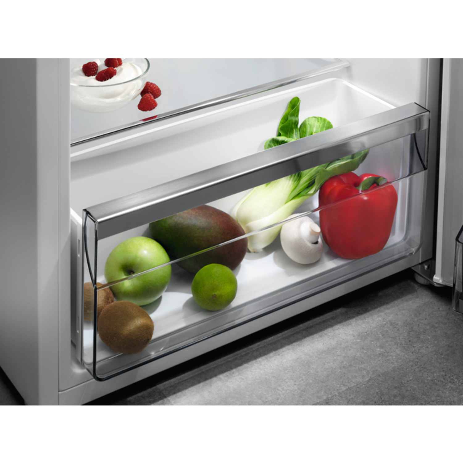 Refrigerator drawer with fruits and vegetables: mango, lime, green apple, pepper.