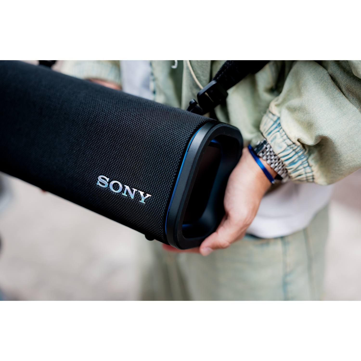 Une personne tenant une enceinte Sony noire, en gros plan.