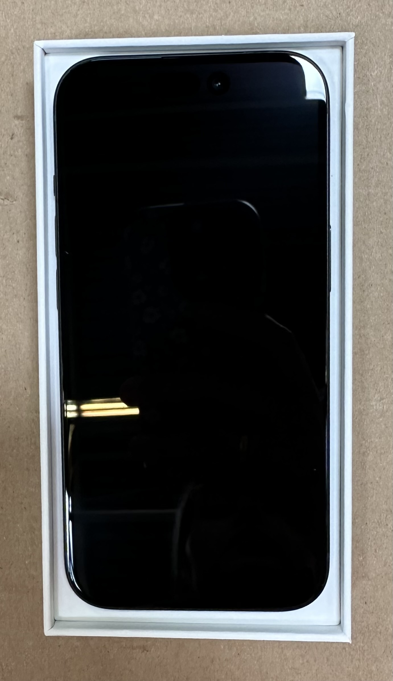 Czarny telefon w białym pudełku, ekran czarny, aparat u góry.