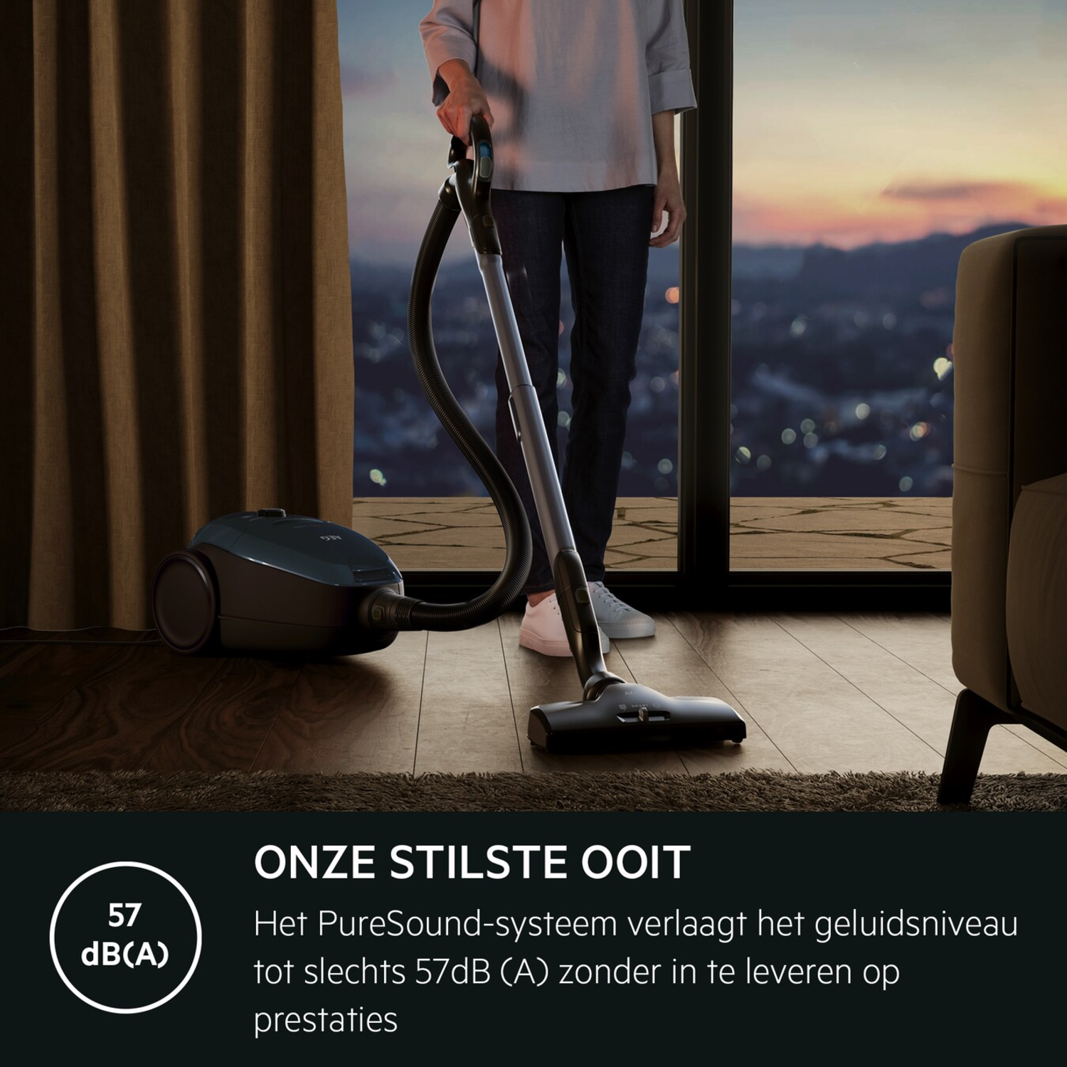 Person vacuuming a room. The vacuum is dark blue, with text: 'Onze stilste ooit'.