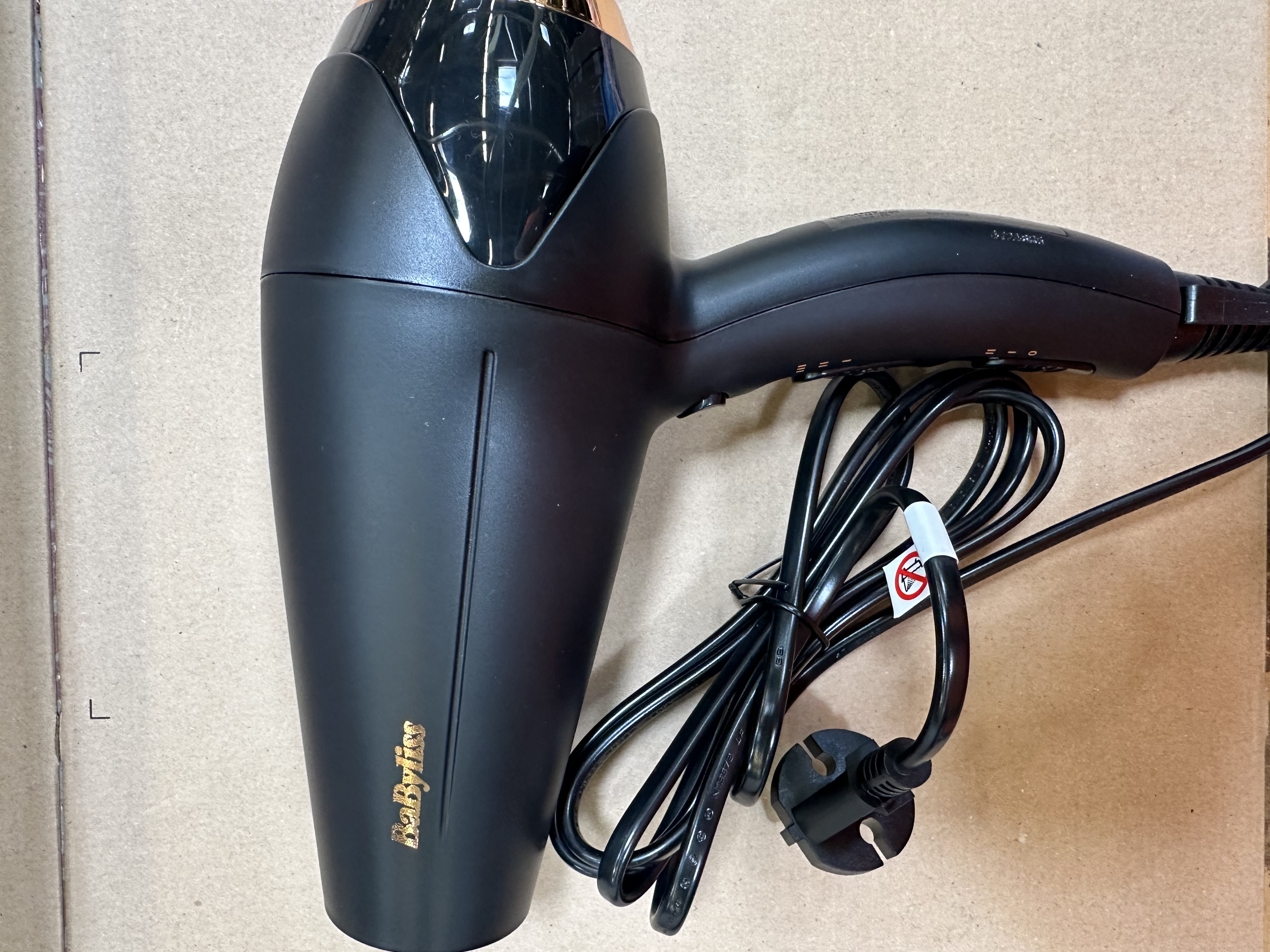 Czarna suszarka do włosów. Czarny uchwyt z przyciskami i przewodem zasilającym.