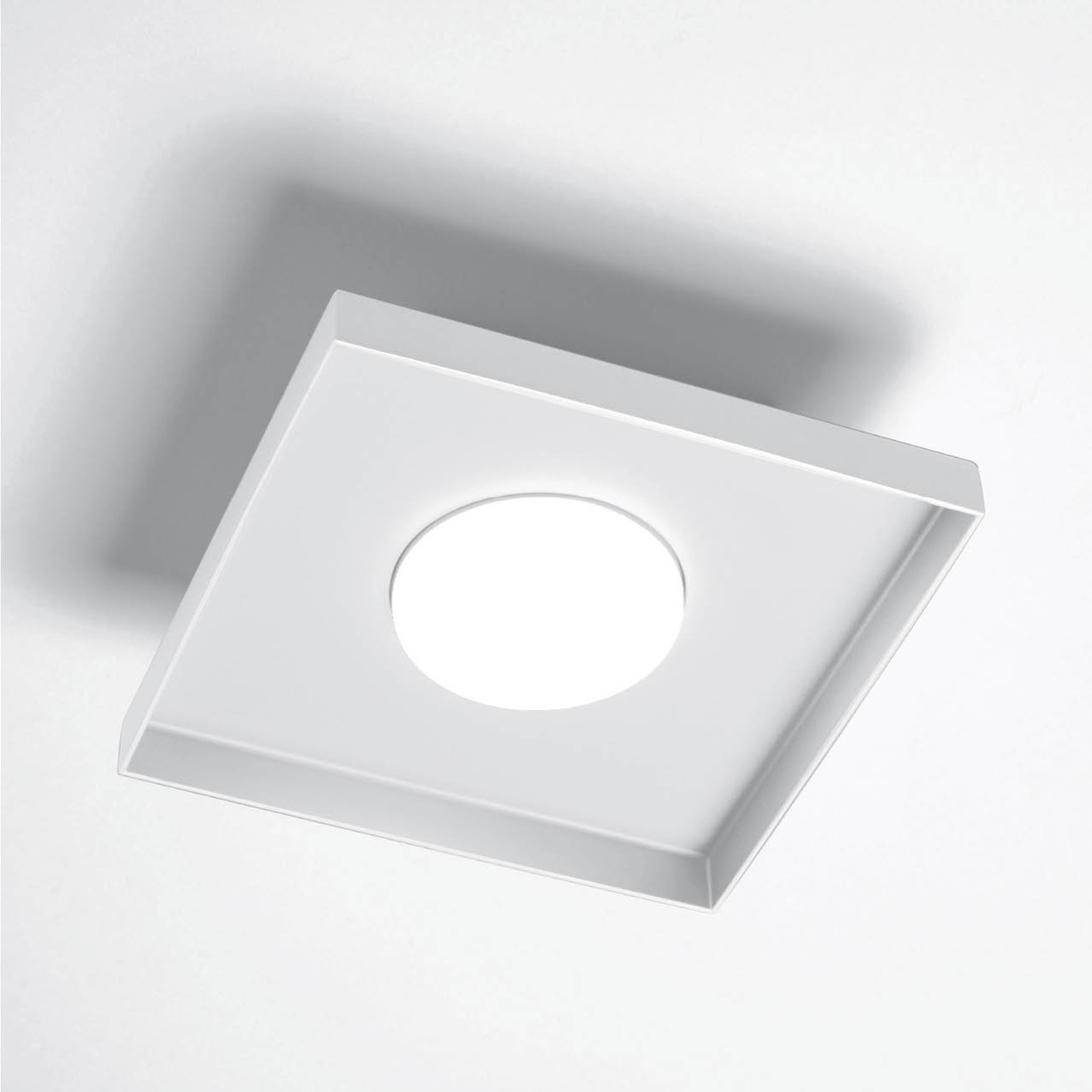 Un quadrato bianco con un foro circolare al centro, che proietta un'ombra.