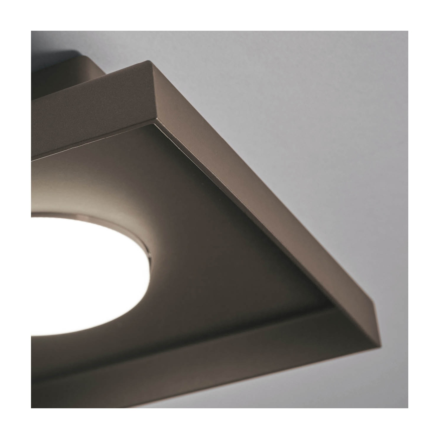 Primo piano di un apparecchio di illuminazione da soffitto quadrato marrone scuro. All'interno è visibile una luce circolare.