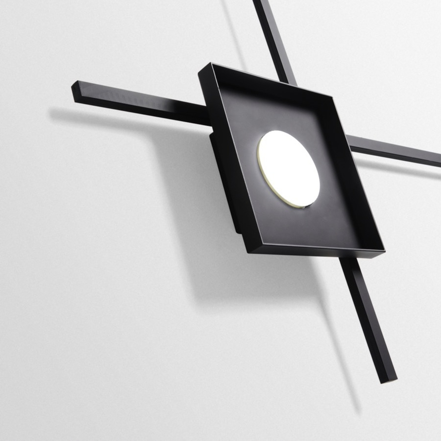Un muro nero con un apparecchio di illuminazione geometrico. Ha una forma quadrata con un cerchio.