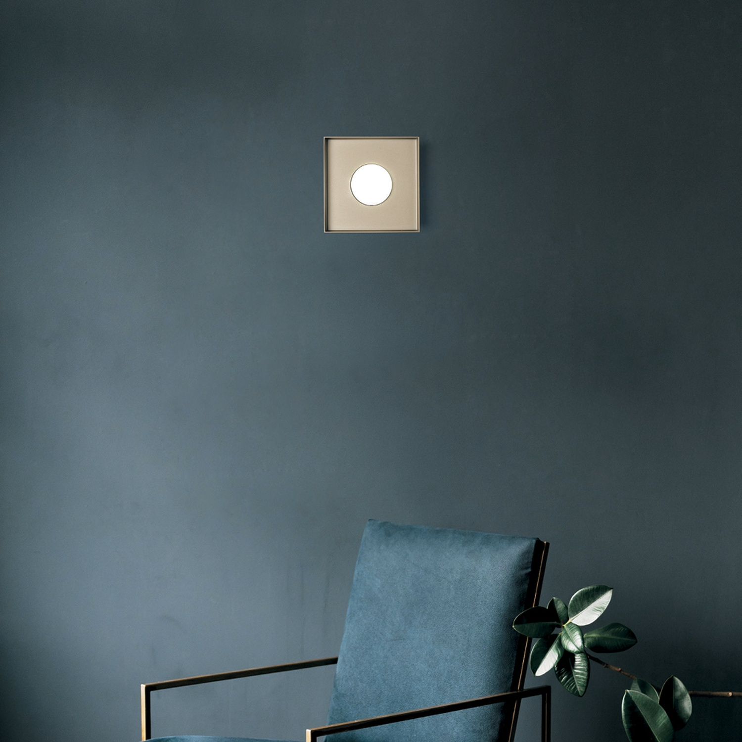 Scena d'interni moderna. Poltrona blu, finiture dorate, lampada bianca su muro blu. Pianta a destra.