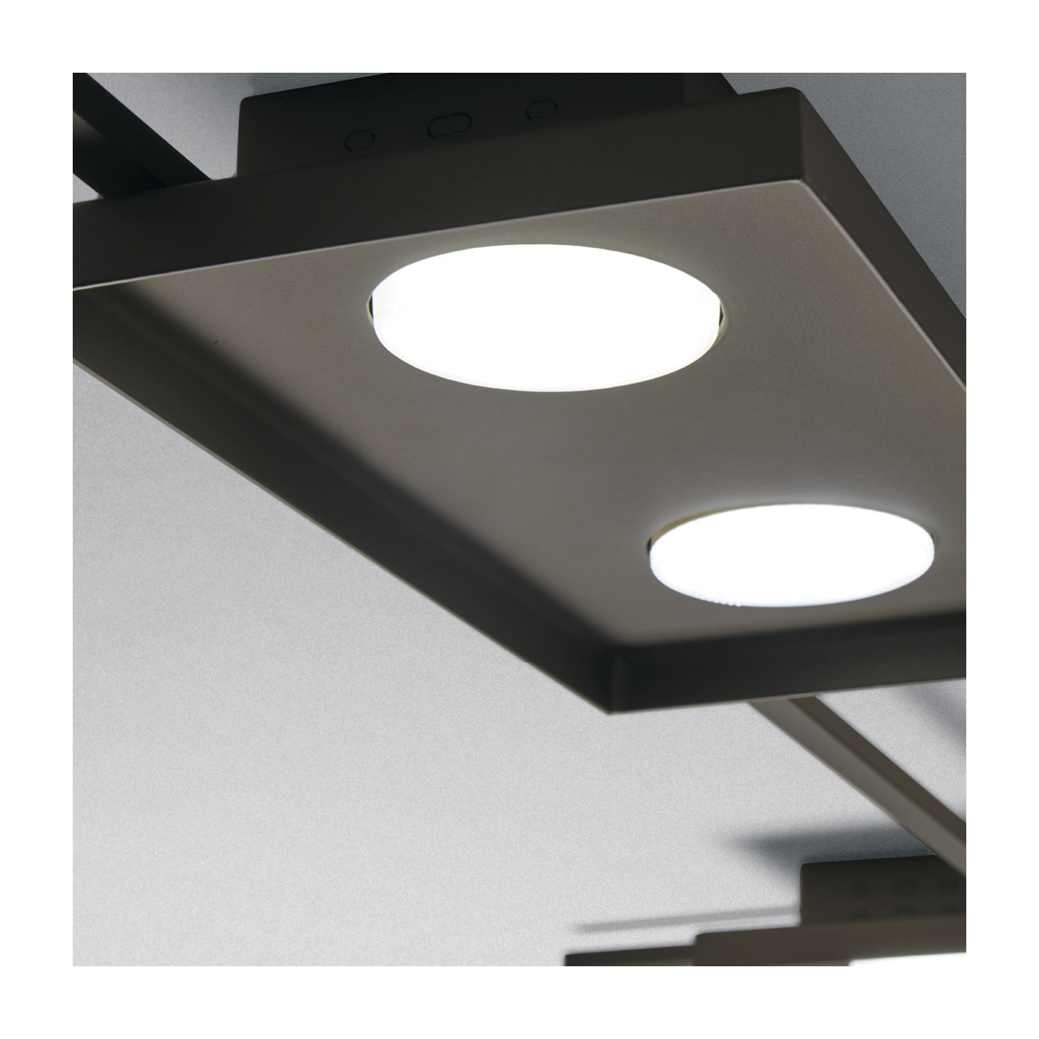 Due plafoniere con sorgenti luminose circolari. Le luci sono montate su una lunga base rettangolare.