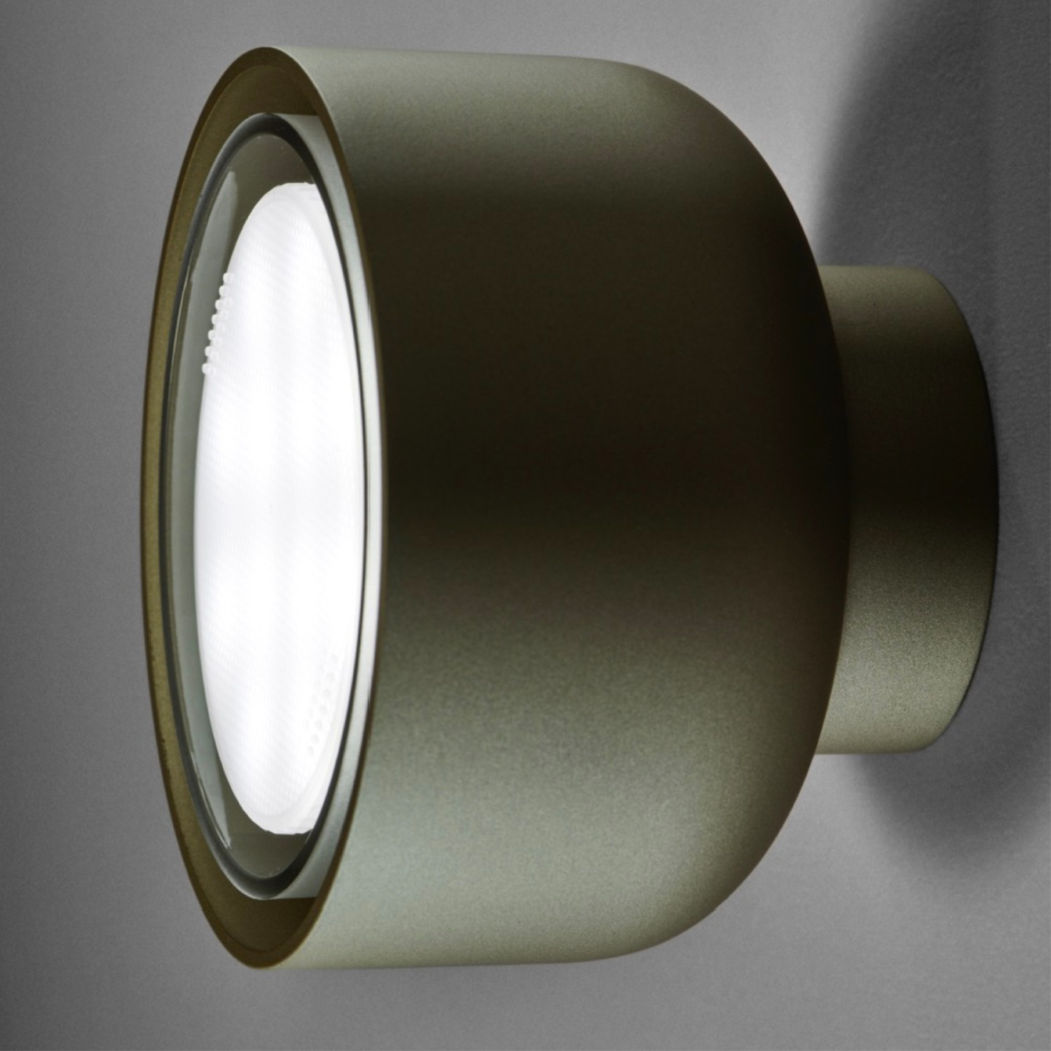 Una lampada da parete, verde oliva, con una luce brillante. L'apparecchio è un design a semicerchio.