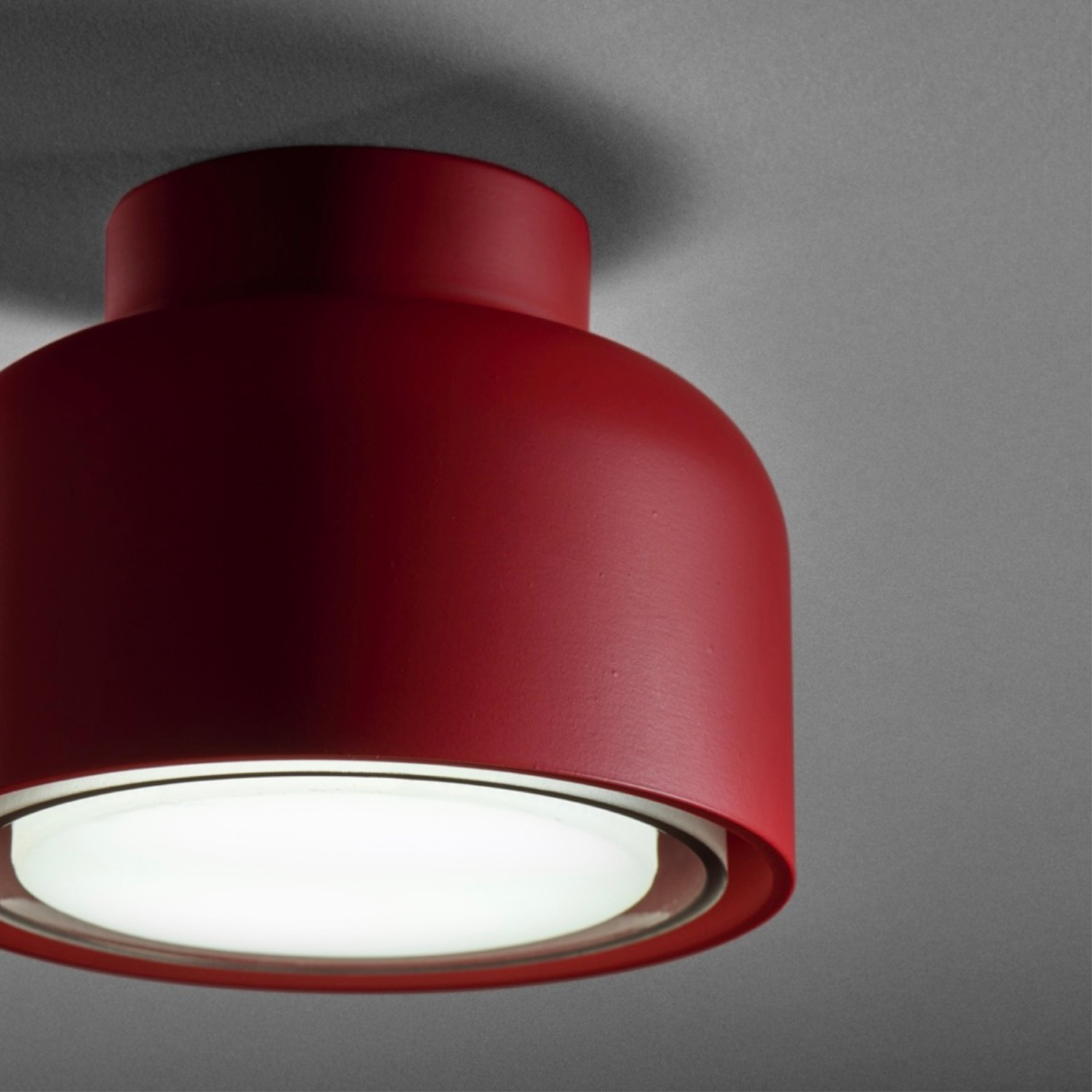 Lampada da soffitto rossa con luce interna bianca e sfondo grigio.