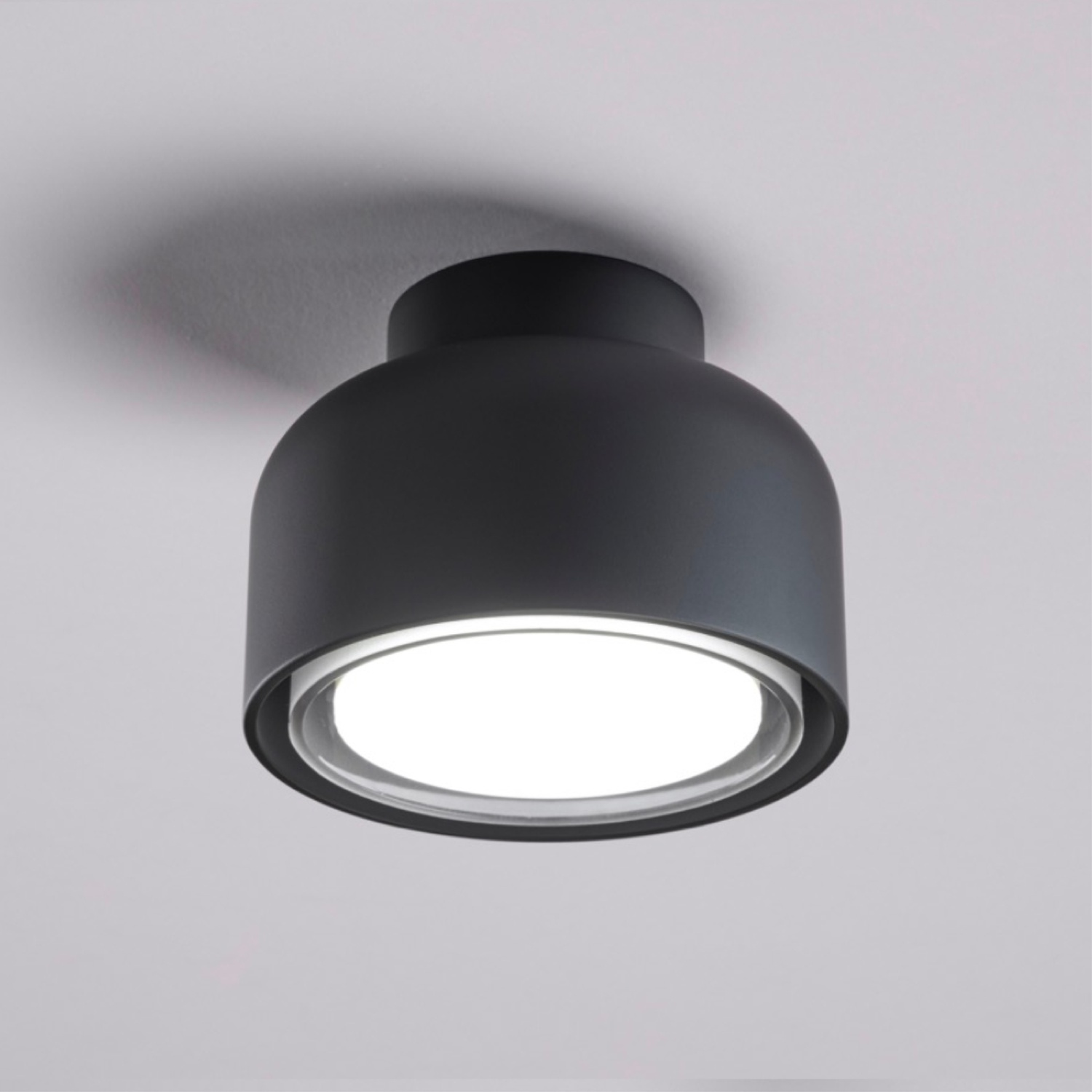 Lampada da soffitto nera a forma di cupola con luce interna brillante e anello trasparente.