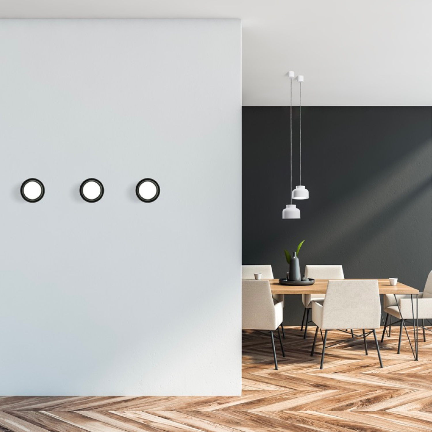 Tre luci circolari su un muro bianco, con tavolo e sedie in una stanza.
