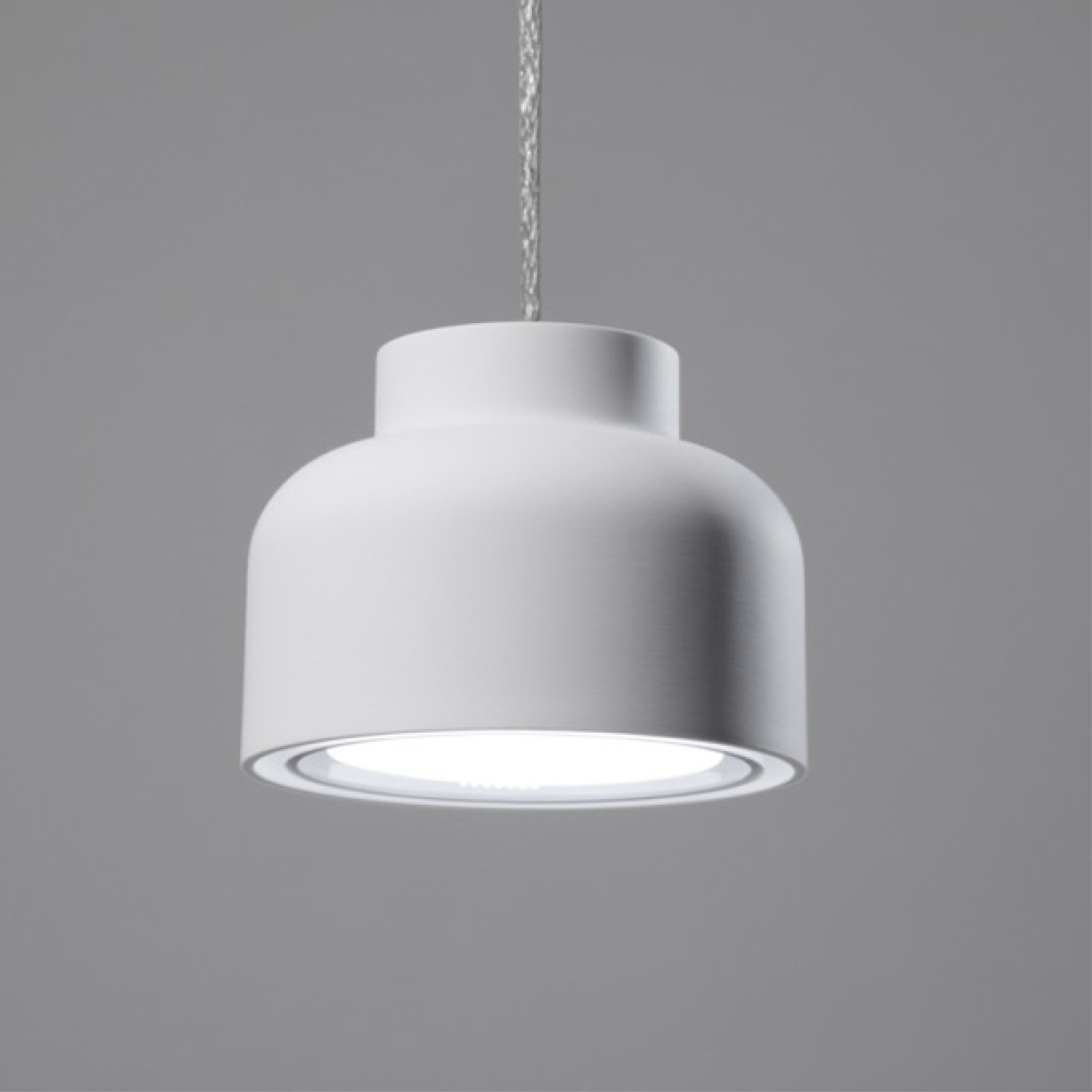 Una stanza con lampade a sospensione color verde acqua, poltrone blu e un mobile in legno.