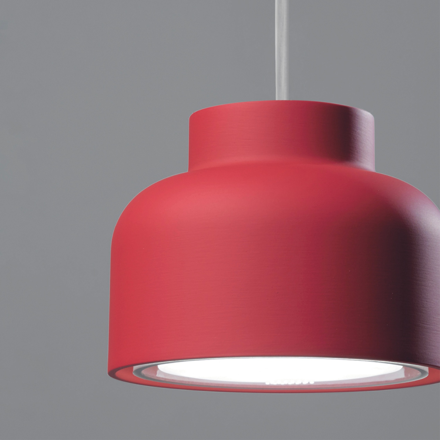 Lampada a sospensione rossa con interno bianco.