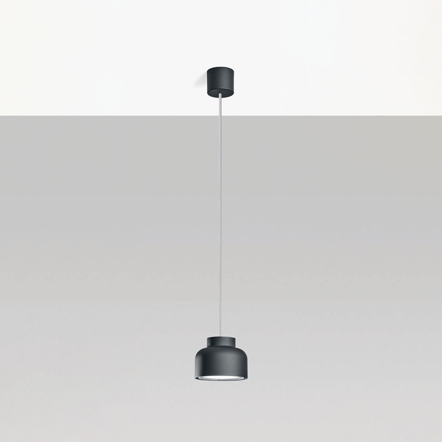 Una lampada a sospensione nera appesa al soffitto con un cavo bianco.