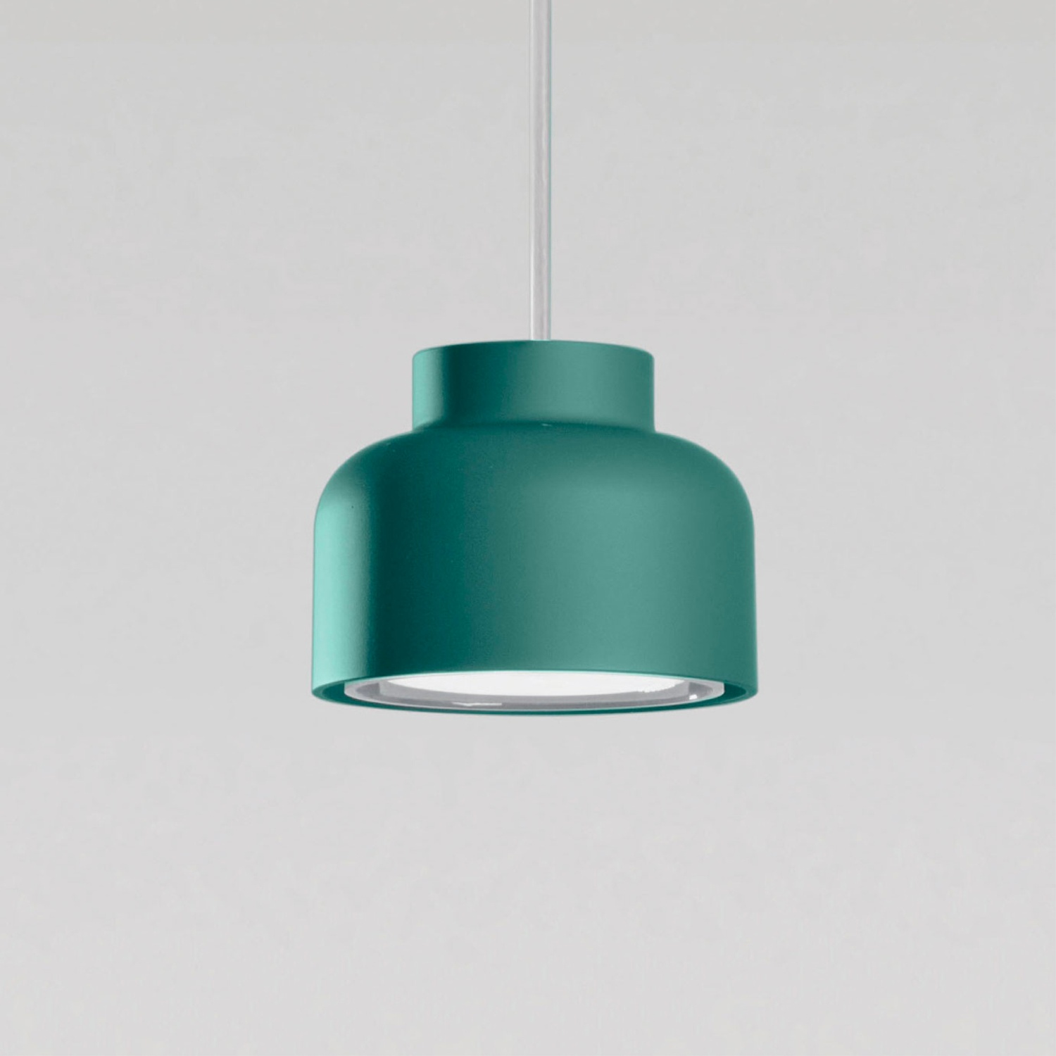 Una lampada a sospensione turchese appesa a un sottile cavo bianco. La luce è a forma di cupola.