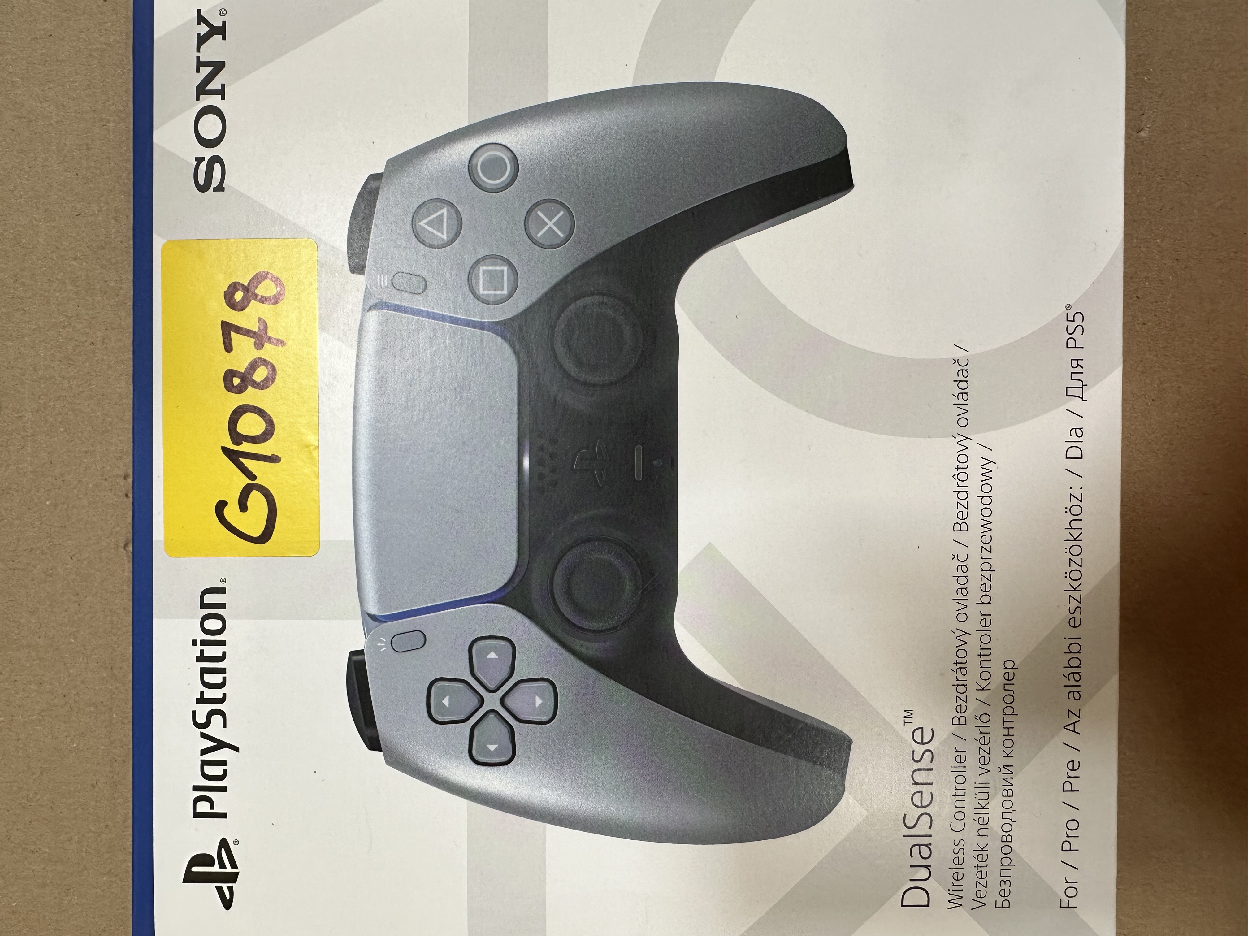 Szary kontroler Sony Playstation na pudełku, żółta naklejka.