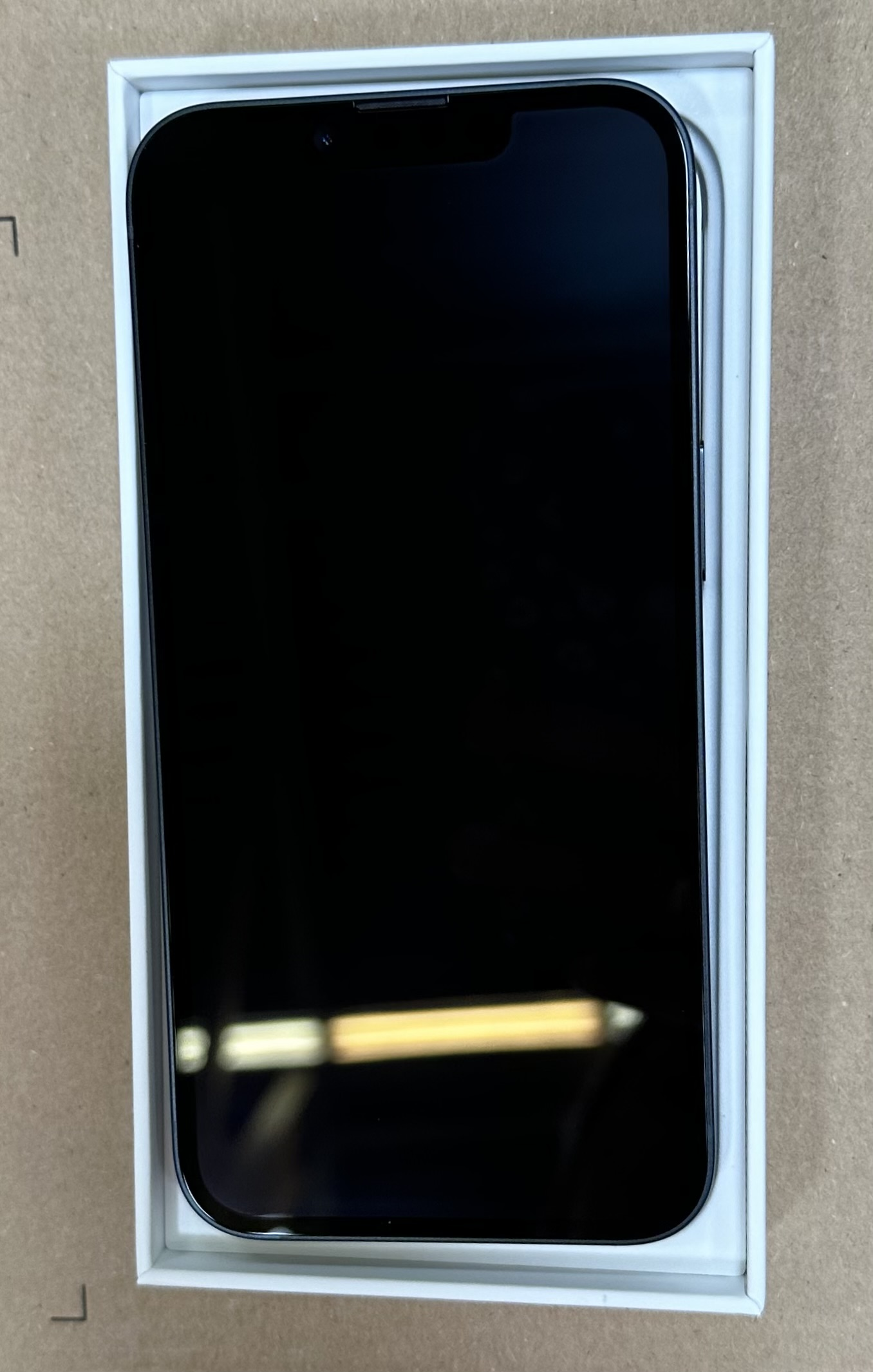 Czarny smartfon w otwartym pudełku. Ekran jest w pełni widoczny i ciemny.