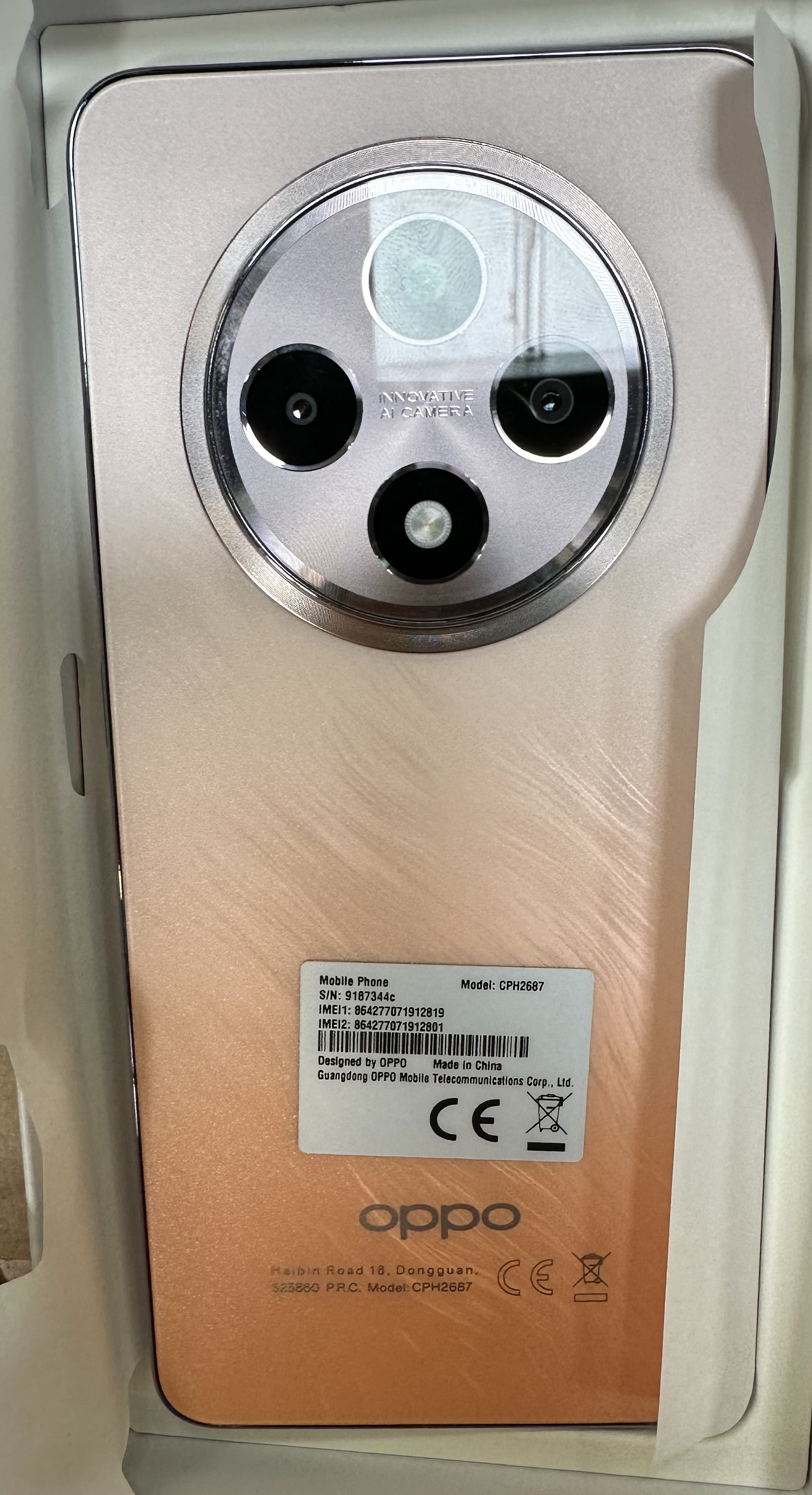 Telefon Oppo w pudełku, widok z tyłu. Posiada zestaw kamer i logo Oppo.